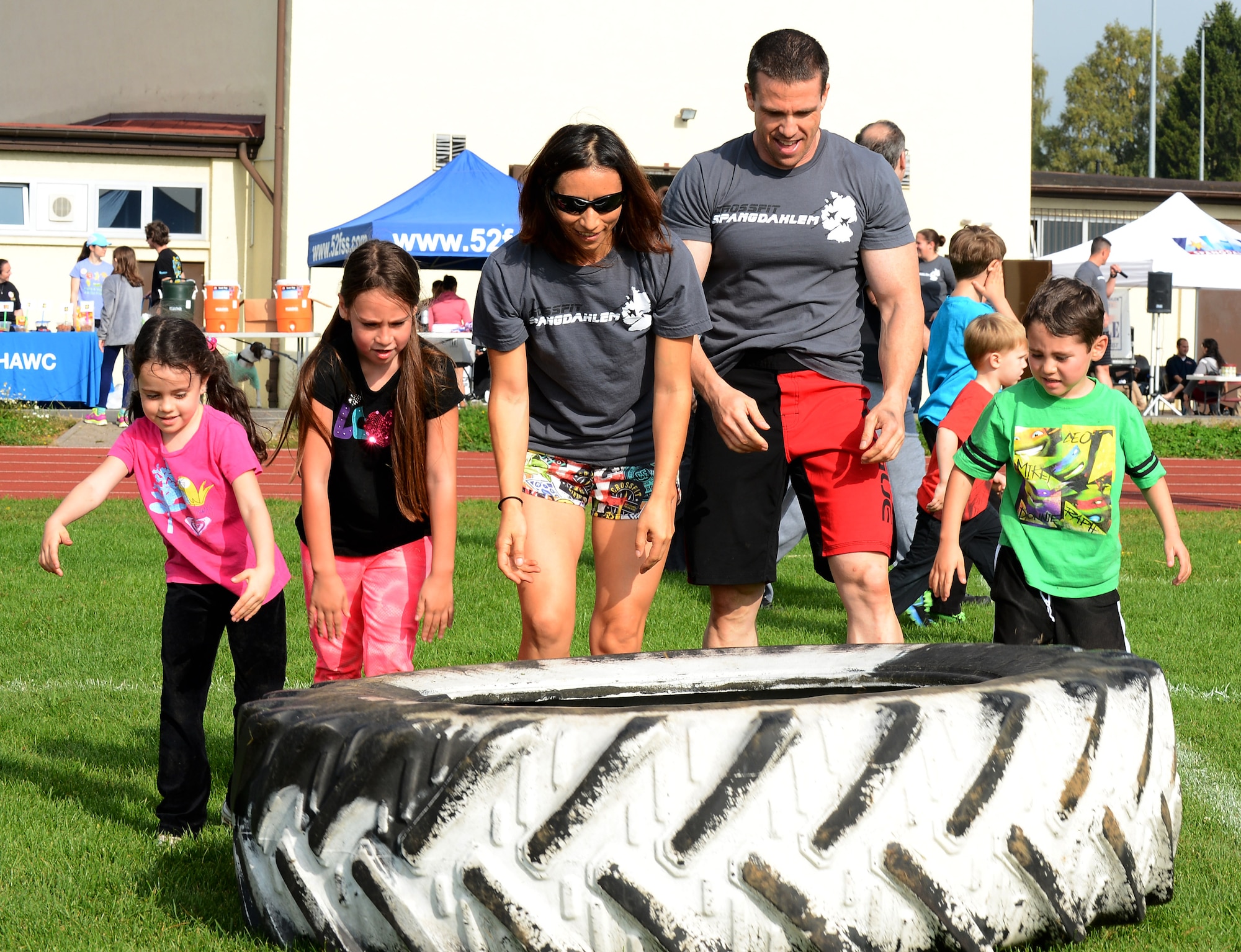 The Salzman family flips over a tire during Fit Family Field Day at the outdoor track on Spangdahlem Air Base, Germany, Sept. 20, 2014. Exercises included tire flipping, potato sack races, bear crawling and more. (U.S. Air Force photo by Airman 1st Class Luke J. Kitterman/Released)


