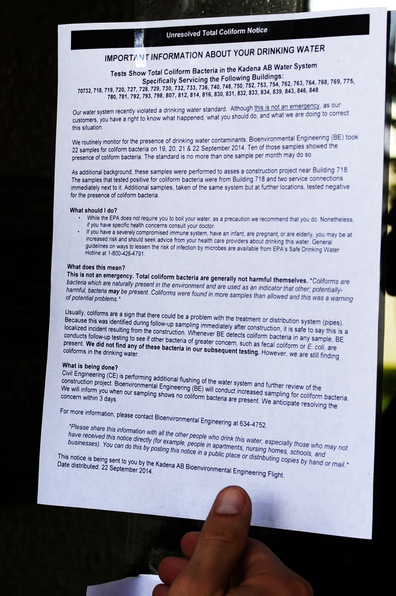 An Airman from the 18th Aerospace Medicine Squadron Bioenvironmental Engineering flight places a notice on a building door about the current drinking water situation for select locations on Kadena Air Base, Japan, Sept. 23, 2014. After a construction project on base broke a water pipe, the Bioenvironmental Engineering flight tested the site for contamination and the 18th Civil Engineering Squadron is flushing the water system. (U.S. Air Force photo by Senior Airman Marcus Morris/Released)