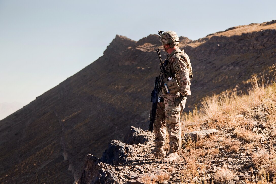 A U.S. soldier provides security while soldiers patrol up Pride Rock mountain for a reenlistment ceremony in Paktya province, Afghanistan, Sept. 21, 2014.