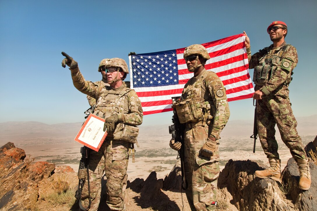 U.S. Army Col. Cameron M. Cantlon, left, points toward Forward Operating Base Lightning while U.S. Army Sgt. Andrew Vance, center, looks on from the top of Pride Rock mountain n Paktya province, Afghanistan, Sept. 21, 2014. Soldiers conducted a patrol and held a  reenlistment ceremony for Vance atop Pride Rock. Cantlon is commander of the 3rd Cavalry Regiment, and Vance is assigned to the 1st Squadron, 3rd Cavalry Regiment.