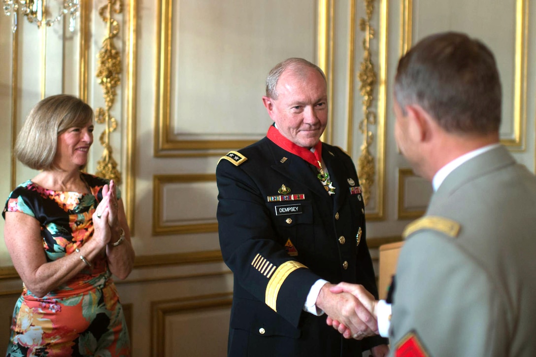 Wearing the French Legion of Honor medal, U.S. Army Gen. Martin E. Dempsey, center, chairman of the Joint Chiefs of Staff, shakes hands with French Army Gen. Pierre de Villiers, chief of defense staff, as Dempsey's wife, Deanie, looks on in Paris, Sept. 18, 2014.