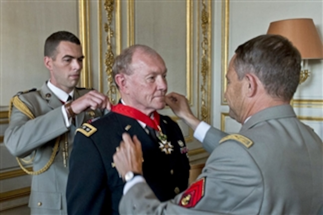 French Army Gen. Pierre de Villiers, foreground, chief of defense staff, helps place the French Legion of Honor medal on U.S. Army Gen. Martin E. Dempsey, center, chairman of the Joint Chiefs of Staff, in Paris, Sept. 18, 2014. The medal, established by Napoleon Bonaparte in1802, is the highest decoration in France.