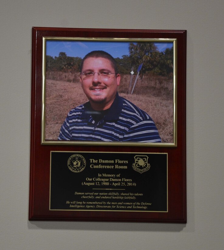 Pictured is a plaque dedicating a conference room at Patrick AFB, Fla., to Damon Flores, a senior network engineer from the Air Force Technical Applications Center’s Operating Location-Technology Coordination, who succumbed to cancer in April 2014.  “It seemed fitting to have Damon’s smiling face hanging on the wall of the room where we discuss so many of our success stories,” said Joseph Convery, director of OL-TC.  (U.S Air Force photo by Susan A. Romano)