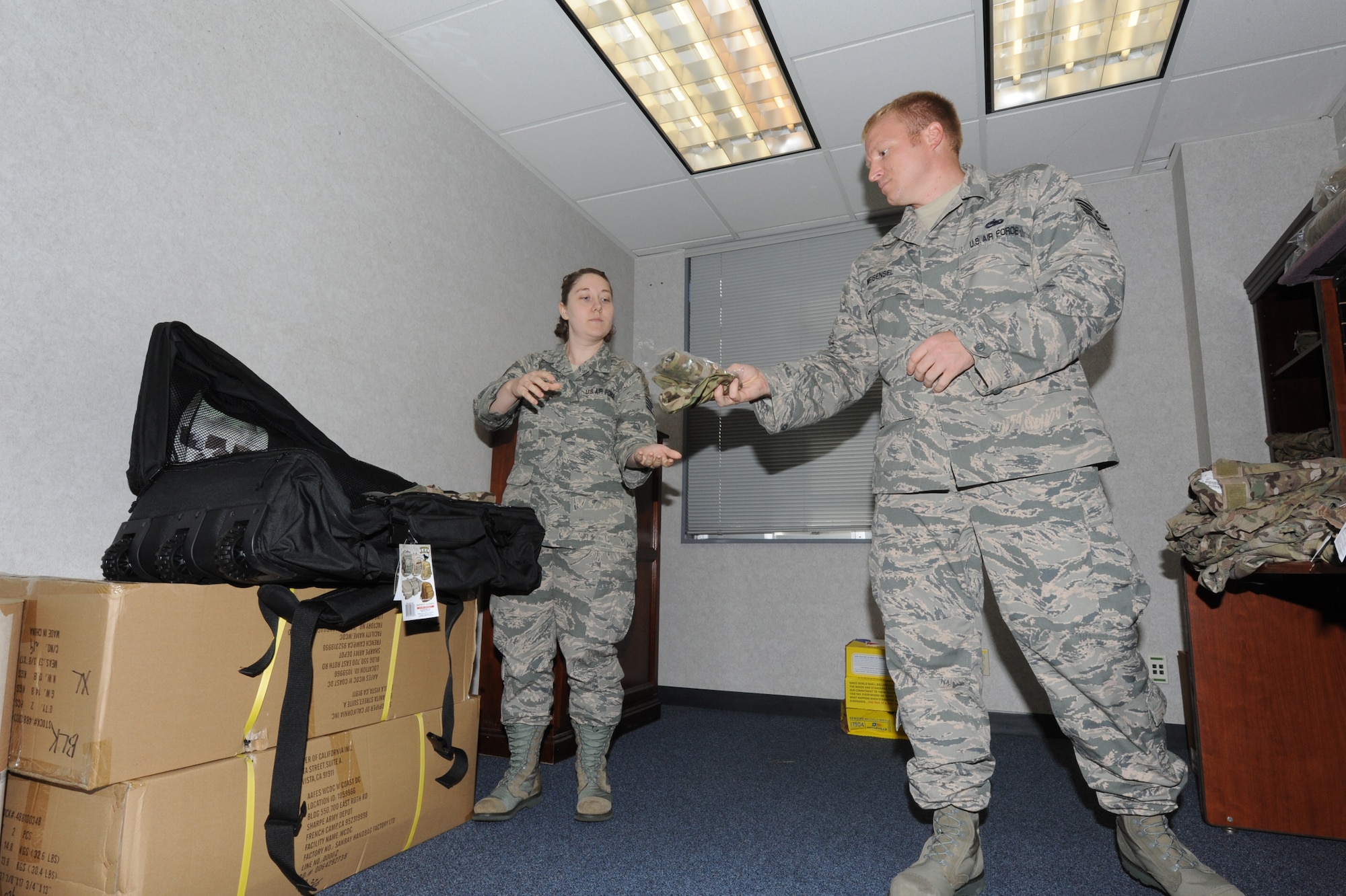 U.S. Air Force Staff Sgt. Jessica Floyd, 733rd Air Mobility Squadron unit security manager (left), assists Tech. Sgt. Benjamin Weisensel, 733rd AMS unit deployment manager (right), in issuing and reorganizing deployment gear on Kadena Air Base, Japan, Sept. 24, 2014. The combat readiness flight of the 733rd Air Mobility Squadron is responsible for all of the logistics for the entire squadron's Airmen, which includes all of the training, deployments, vehicle control and more. (U.S. Air Force photo by Airmen 1st Class 