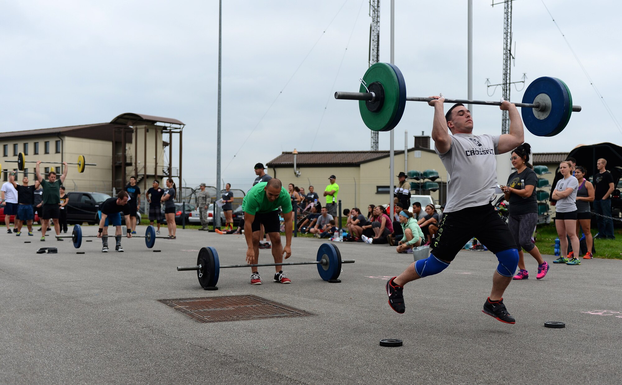Male competitors in the Combat Fitness Eifel Throwdown lift weights as their first exercise at the Combat Fitness Center on Spangdahlem Air Base, Germany, Sept. 20, 2014. This specific lift, known as a clean and jerk, involves a person lifting the bar from the ground to their collar bone and then eventually pushed up over their head. (U.S. Air Force photo by Airman 1st Class Luke J. Kitterman)  