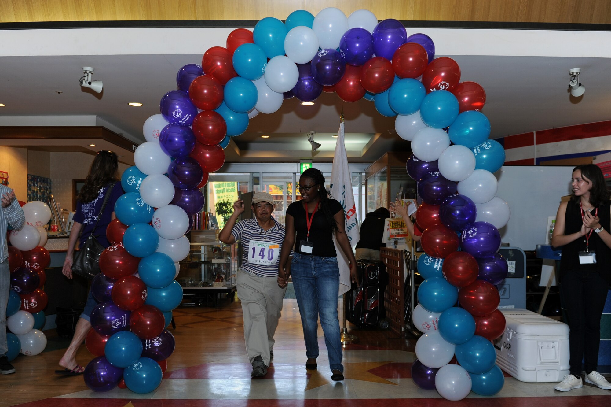 A volunteer leads Hirokazu Fukuda, a Special Olympics athlete, into Seaside Bowl in Mihama, Japan, Sept. 20, 2014. Approximately 300 athletes were greeted by cheers from more than 150 Department of Defense volunteers and 50 volunteer interpreters as they entered the facility to participate in a bowling competition. (U.S. Air Force photo by Airman 1st Class Zade C. Vadnais/Released)