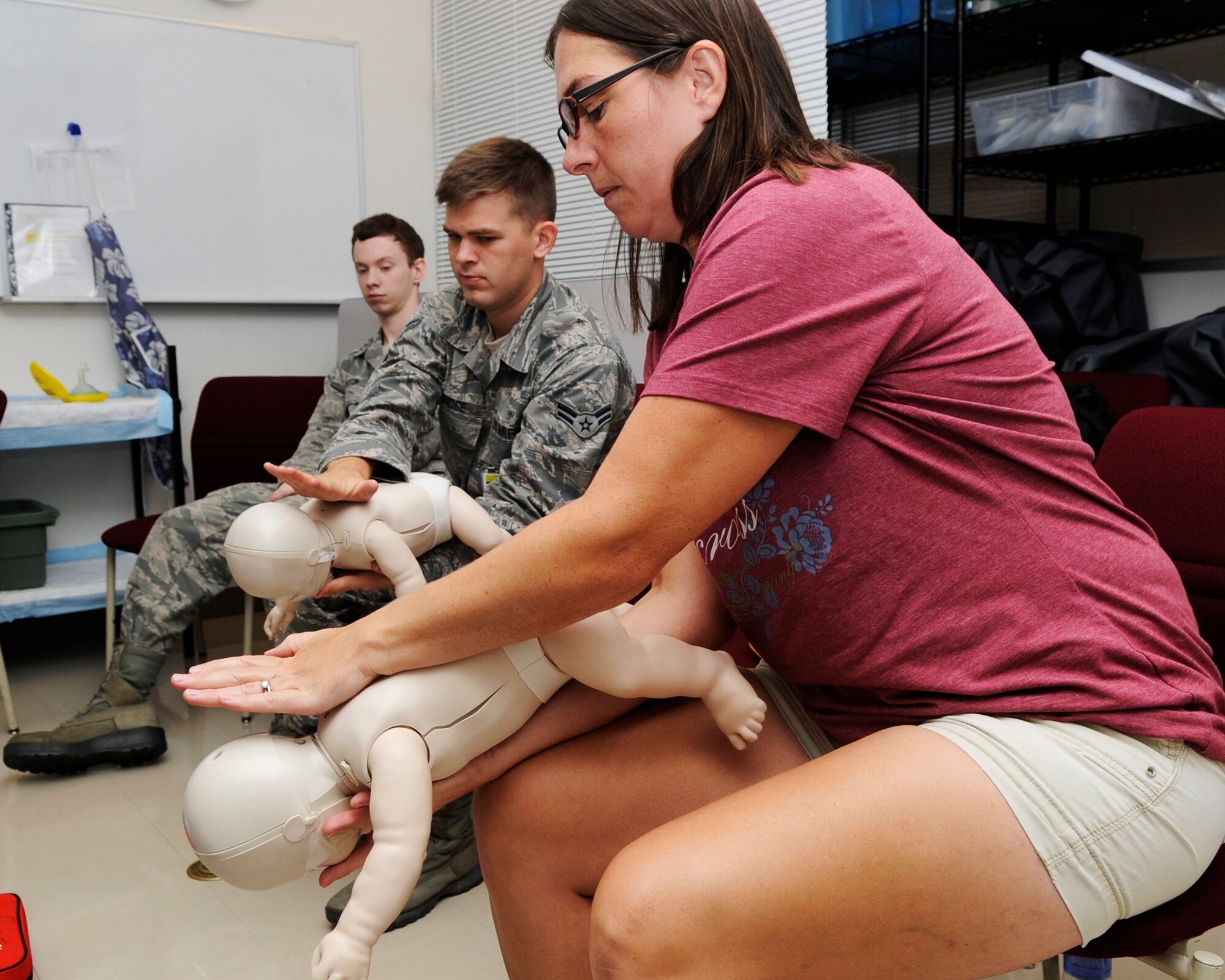 U.S. Air Force Airman 1st Class Paul Aldridge (middle), 18th Medical Operations Squadron family practice, and Rebecca Rouse (right), physician, practice removing stuck objects from a baby’s throat on Kadena Air Base, Japan Sept. 19, 2014. The training was part of a basic life saving skills course that covered the proper use of an Automated External Defibrillator, rescue breathing, abdominal thrust techniques and CPR on adults, children and babies. (U.S. Air Force photo by Senior Airman Marcus Morris/Released)

