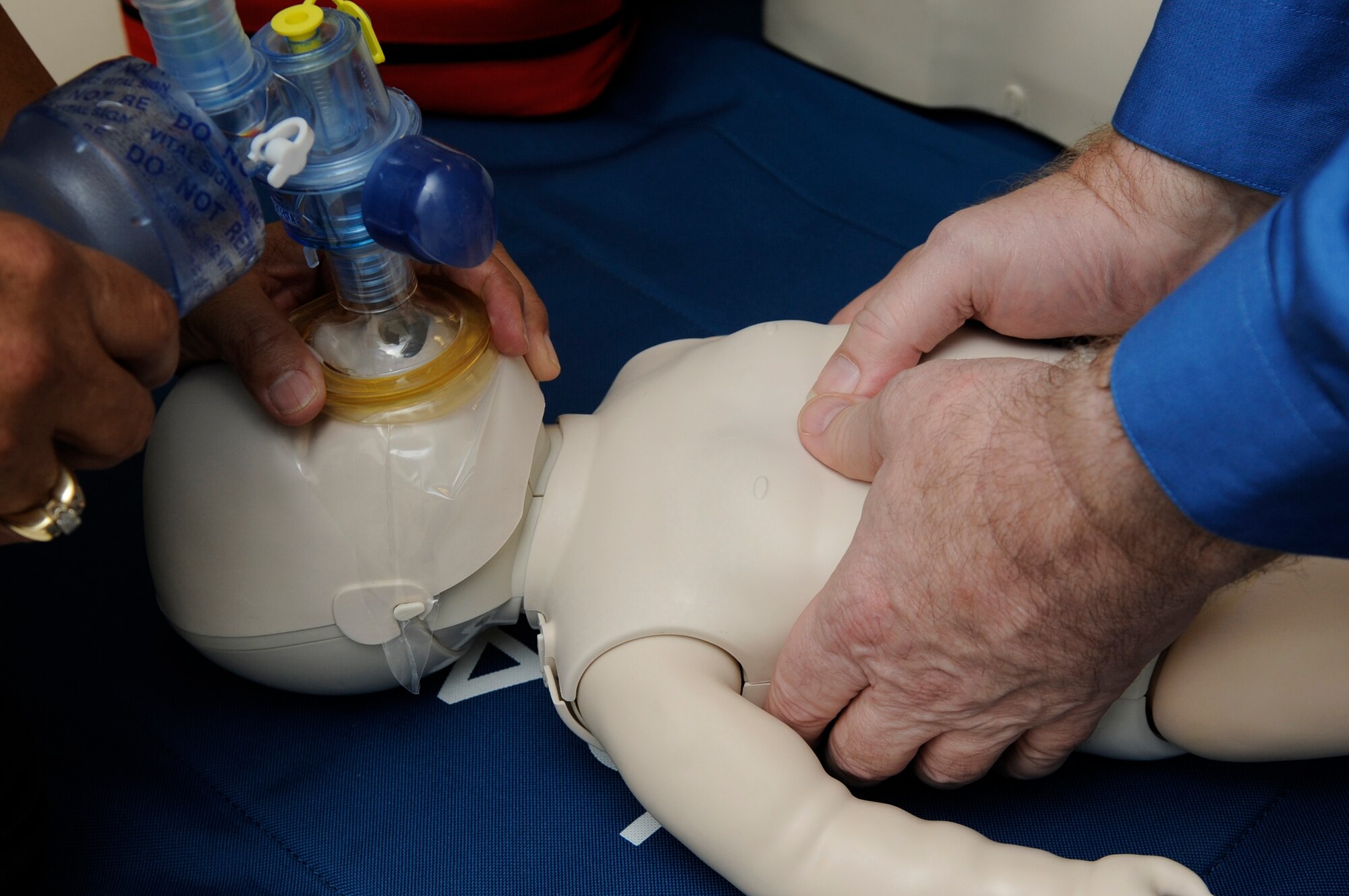 U.S. Air Force medical practitioners practice a two-person CPR technique on a baby simulator on Kadena Air Base, Japan Sept. 19, 2014. The training is part of health care providers’ basic life saving skills, aerovac medics’ skills and a requirement for Emergency Medical Technicians. (U.S. Air Force photo by Senior Airman Marcus Morris/Released)