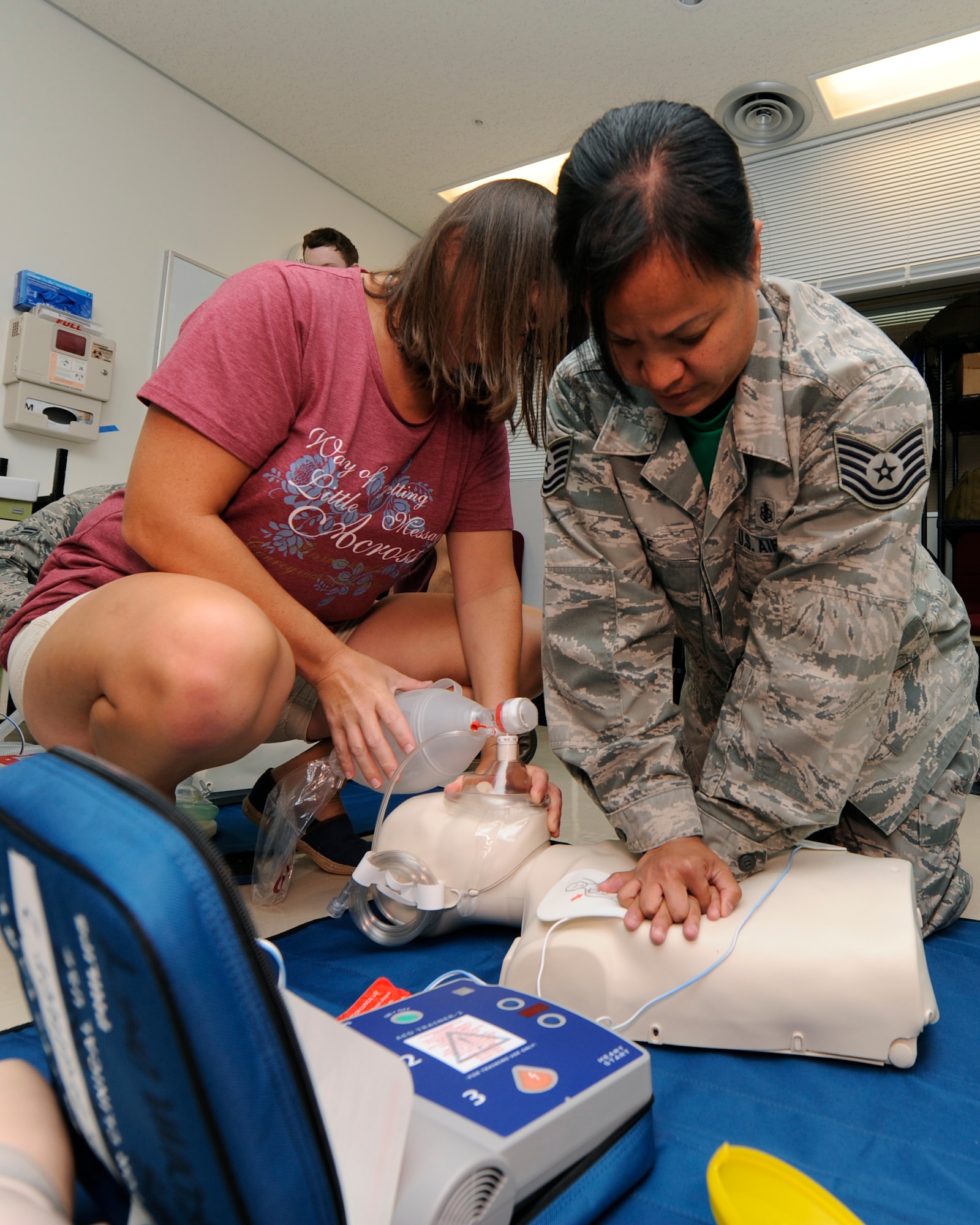 Rebecca Rouse,  physician, and Tech. Sgt. Palle Corazon, 18th Aerospace Medicine Squadron NCO in charge of Public Health, perform CPR while using an Automated External Defibrillator on a training dummy on Kadena Air Base, Japan, Sept. 19, 2014. The medical personnel were trained on how to do one- and two-person rescue breathing and CPR for adults, children and babies. (U.S. Air Force photo by Senior Airman Marcus Morris/Released)