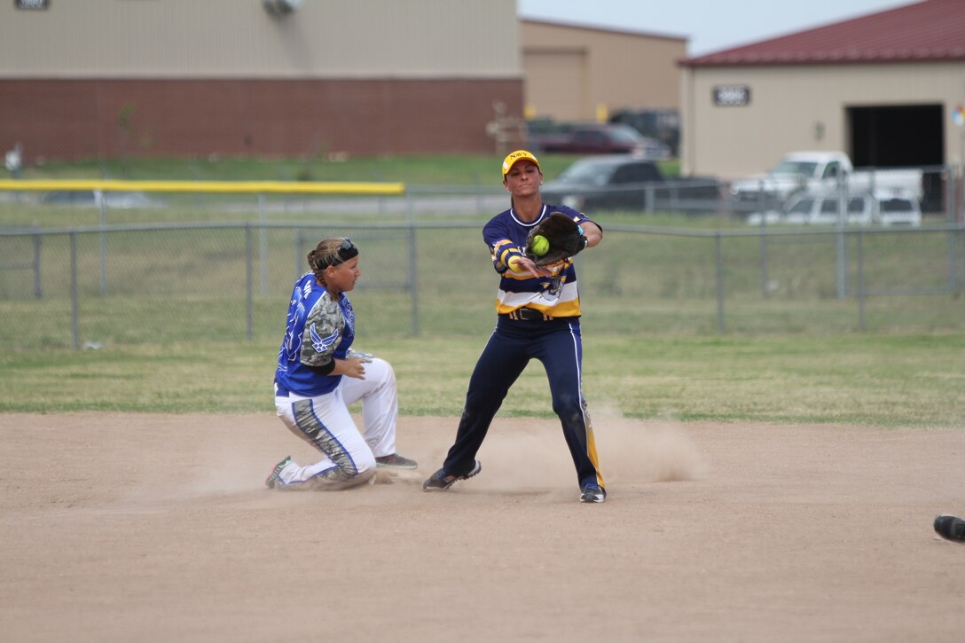 Air Force Master Sgt. Nicole Gill (left) slides safe with Navy Petty Off. 3rd Class Shasta Rodriguez on the catch at the 2014 Armed Forces Softball Championship at Fort Sill, Okla. 14-19 Sept. 