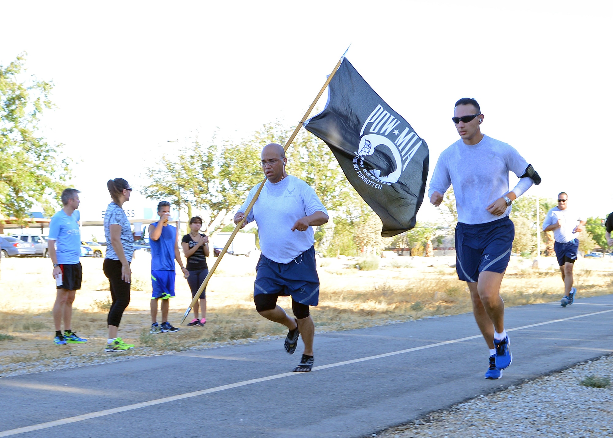 Tech. Sgt. Donald Martinez, 31st Test and Evaluation Squadron NCOIC of Ground Communications, runs with the POW/MIA flag to show his support along with Tech. Sgt. Rommel Blanco (right), 31st TES NCOIC of Maintenance Analysis, during the POW/MIA 5k run held Sept. 19 near the Edwards Express gas station. (U.S. Air Force photo by Jet Fabara)