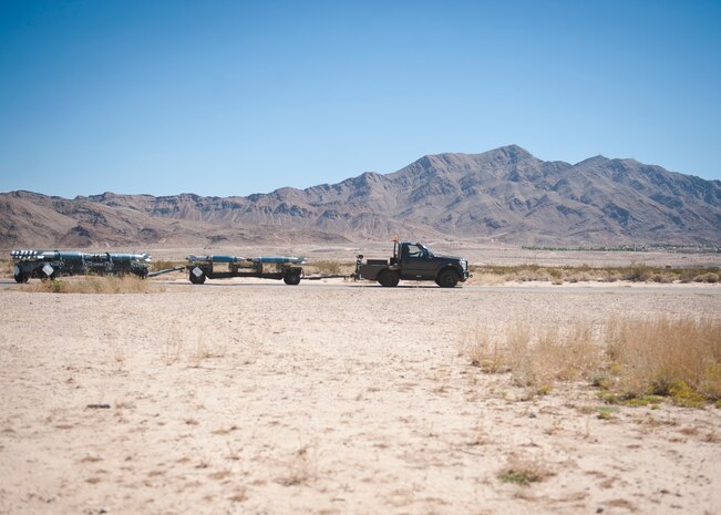 Senior Airman Miguel Vega, 57th Maintenance Squadron munitions line delivery crew chief, transports munitions at Nellis Air Force Base, Nev., Sept. 19, 2014. Line delivery, or ‘Line-D,’ Airmen must maintain a speed of 10 miles per hour or less to ensure the munitions they are towing remain intact. (U.S. Air Force photo by Staff Sgt. Siuta B. Ika)