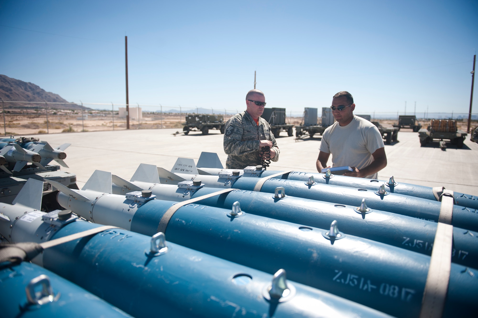 Master Sgt. Donald King, 57th Maintenance Squadron munitions line delivery NCO in charge, and Senior Airman Miguel Vega, 57th MXS munitions line delivery crew chief, inspect munitions after dropping them off on a munitions holding pad at Nellis Air Force Base, Nev., Sept. 19, 2014. Nellis accounts for approximately 40 percent of Air Combat Command’s total munitions expenditures. (U.S. Air Force photo by Staff Sgt. Siuta B. Ika)