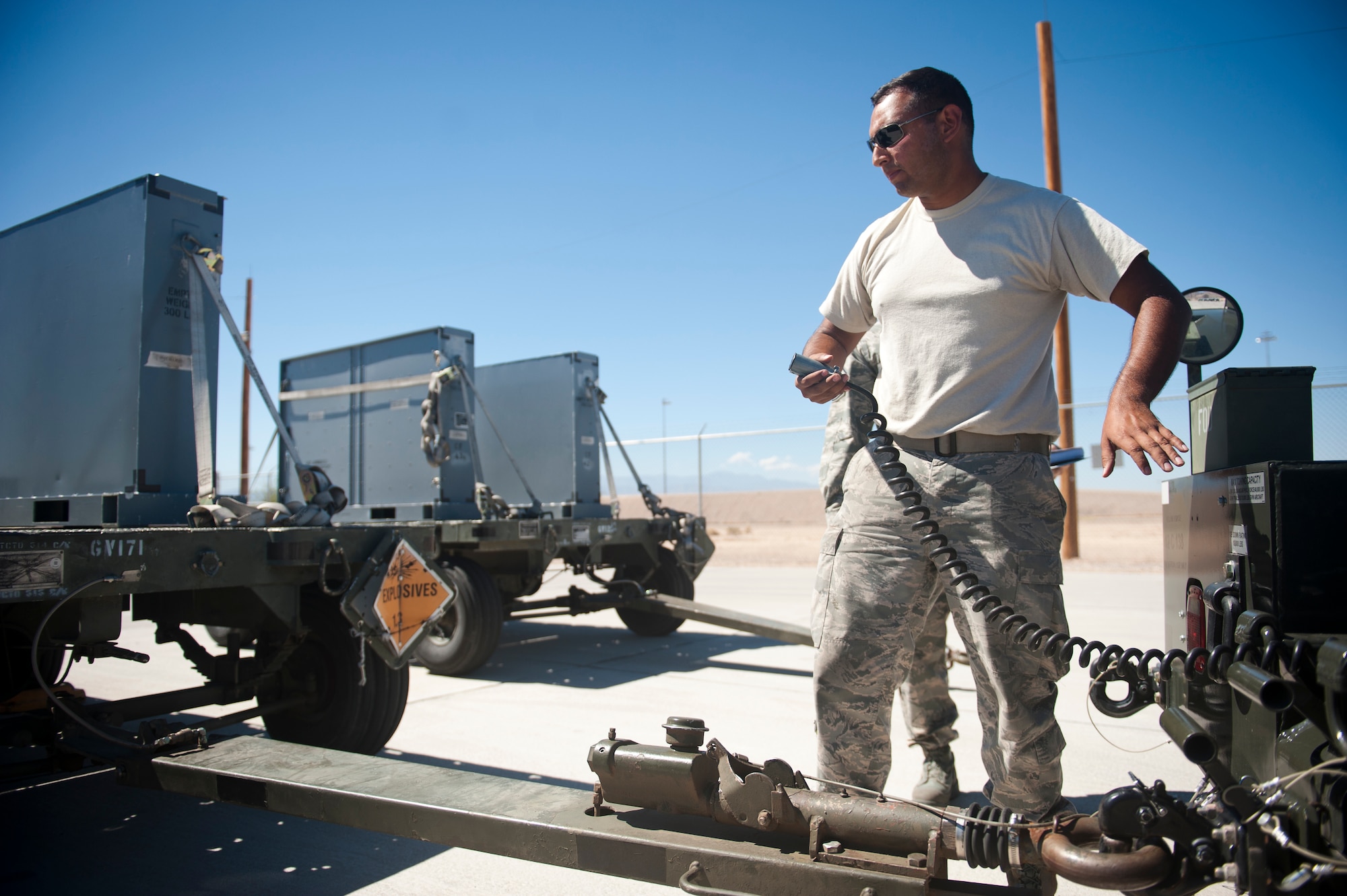 Senior Airman Miguel Vega, 57th Maintenance Squadron munitions line delivery crew chief, hooks up a light cable to a munitions trailer at Nellis Air Force Base, Nev., Sept. 19, 2014. To ensure their trucks and trailers are able to safely make multiple trips transporting munitions from the munitions storage area to the flight line – a distance of approximately eight miles – each driver is held responsible for the daily accounting and maintenance of their equipment. (U.S. Air Force photo by Staff Sgt. Siuta B. Ika)