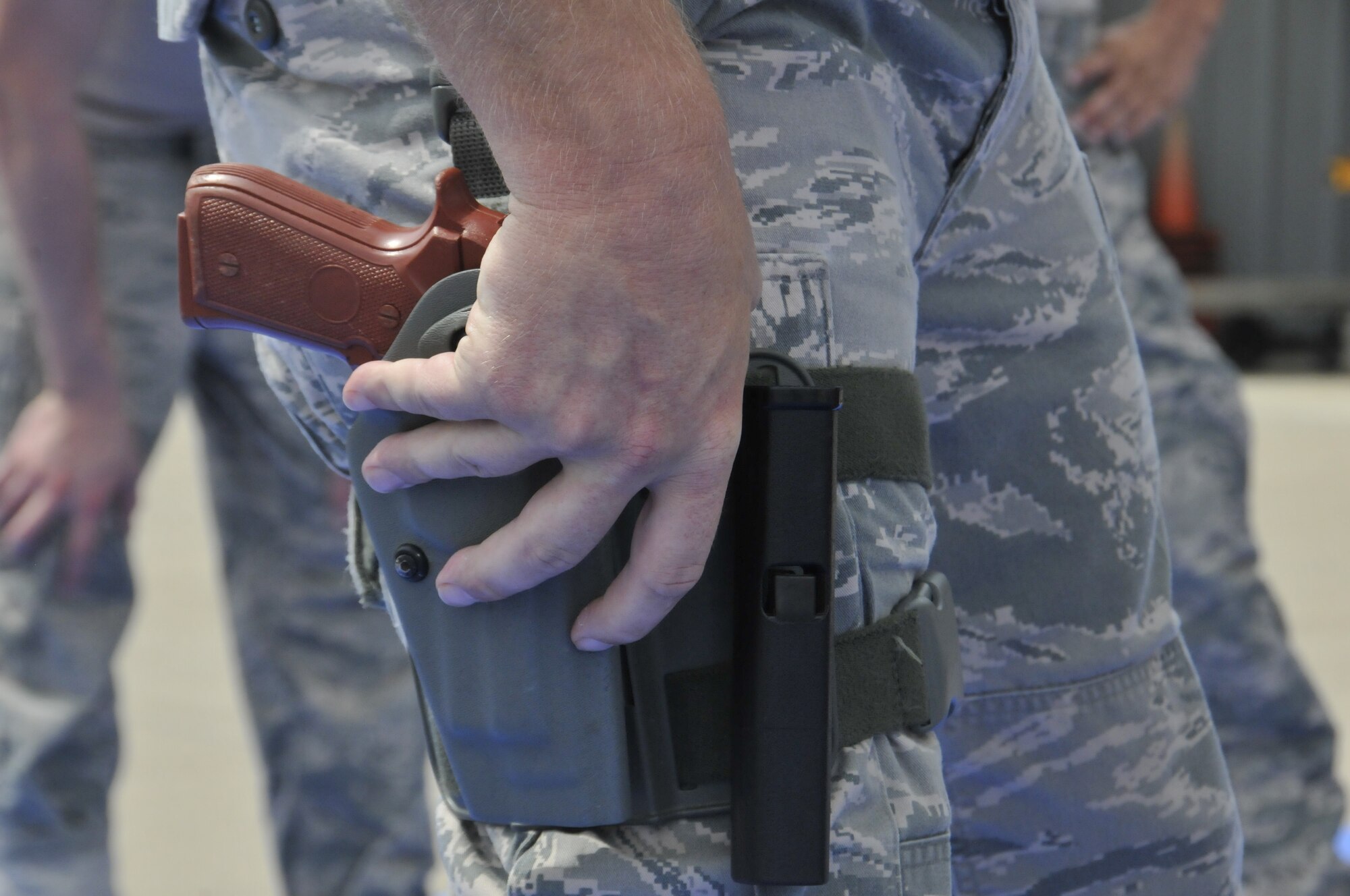 Tech. Sgt. Bradley Hobbs, a 188th Security Forces Squadron combative instructor, secures a training pistol replica in his holster during a training event held at Ebbing Air National Guard Base, Fort Smith, Arkansas, Sept. 6, 2014. The event, held during a unit training assembly, strengthened the squadron’s mission readiness. (U.S. Air National Guard photo by Staff Sgt. John Suleski/Released)