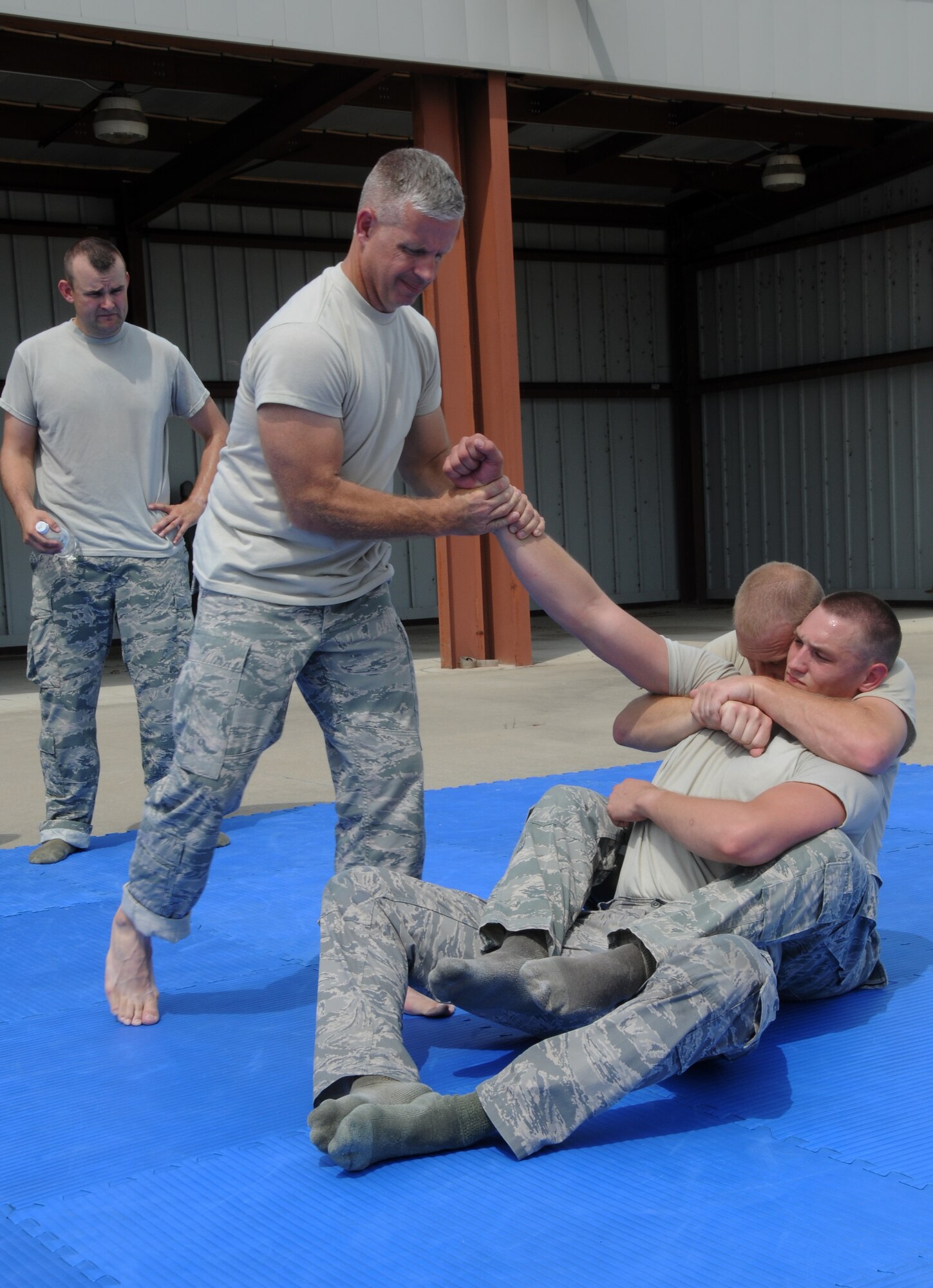 Tech. Sgt. Bradley C. Hobbs, Tech. Sgt. Timothy J. Holland and Senior Airman Mason E. Redding show members of the 188th Security Forces Squadron how to perform a technique during combative training at Ebbing Air National Guard Base, Fort Smith, Arkansas on Sept. 6, 2014. (U.S. Air National Guard photo by Airman 1st Class Cody Martin/Released)