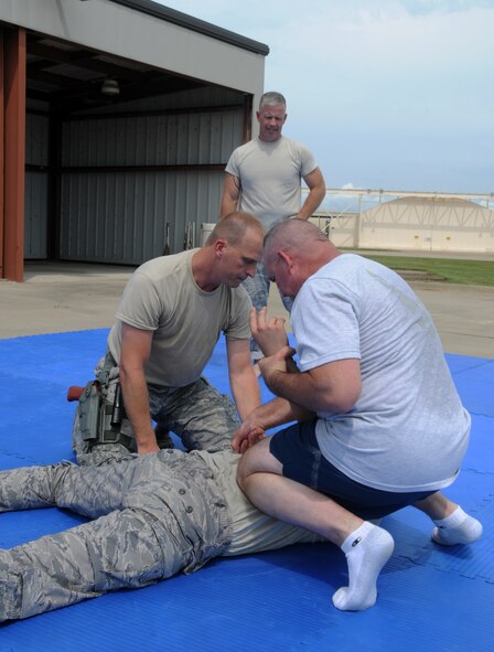 Master Sgt. Chad D. West, Tech. Sgt. Bradley C. Hobbs and Tech. Sgt. Timothy J. Holland shows a technique to Senior Airman Mason E. Redding during combative training at Ebbing Air National Guard Base, Fort Smith, Arkansas on Sept. 6, 2014. All four Airmen members of the 188th Security Forces Squadron (U.S. Air National Guard photo by Airman 1st Class Cody Martin/Released)