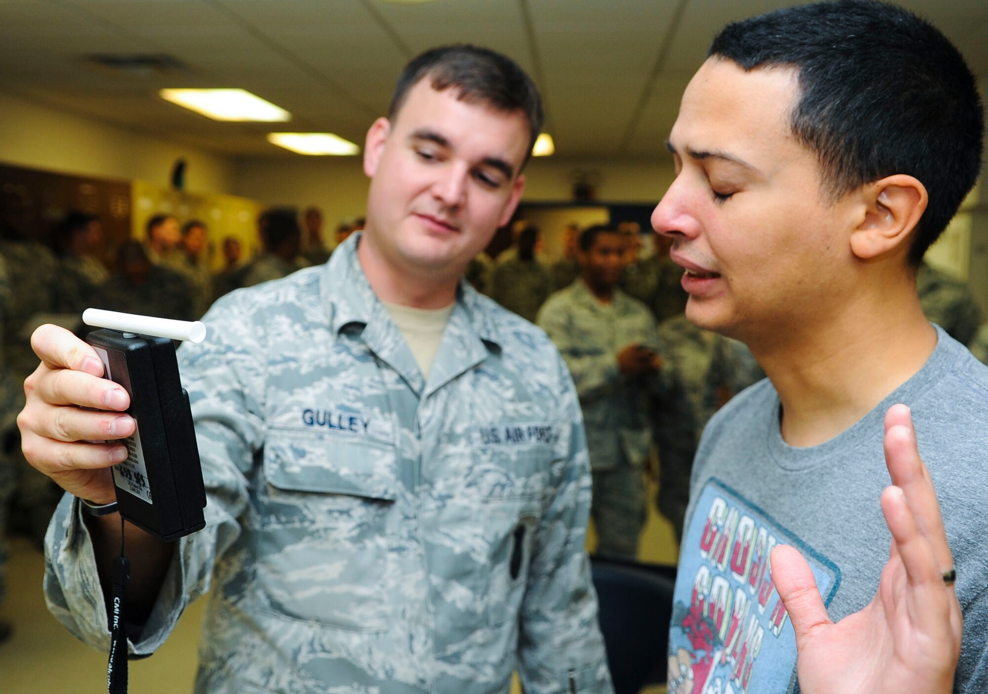 U.S. Air Force Staff Sgt. Ryan Gulley, 633rd Security Forces Squadron unit trainer, looks at a disbelieving volunteer’s blood alcohol content level during a “driving” under the influence training exercise at Langley Air Force Base, Va., Sept. 23, 2014. Gulley said the realistic training exercise is the best way to show Airmen critical law enforcement skills inside a controlled environment. (U.S. Air Force photo by Senior Airman Austin Harvill/Released)