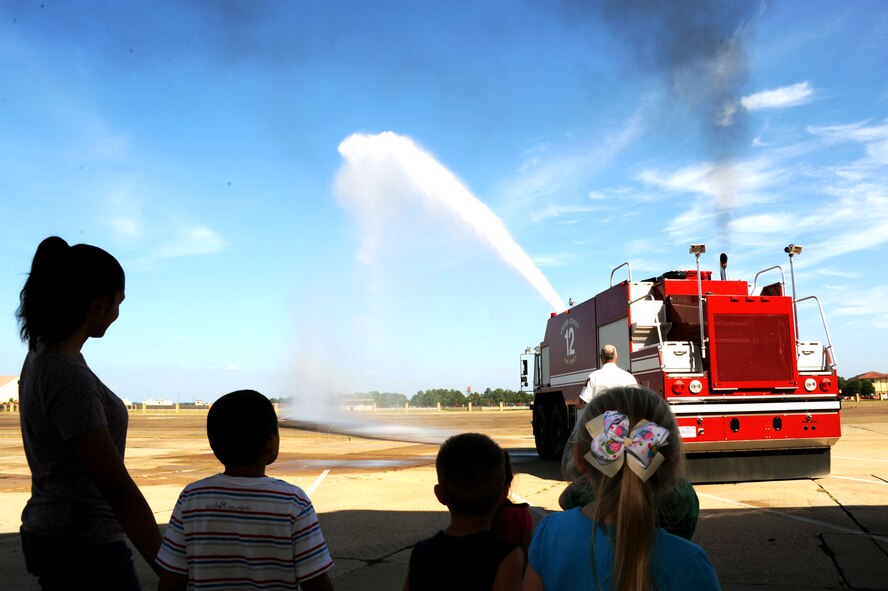 Children from the Maxwell Child Development Center gaze at a fire truck demonstrating the power of its water hose at the fire department at Maxwell Air Force Base, Ala., Sept. 12, 2014. The children toured the bunk rooms, theater, kitchen and a fire truck during their visit. (U.S Air Force photo by Airman 1st Class Alexa Culbert) 