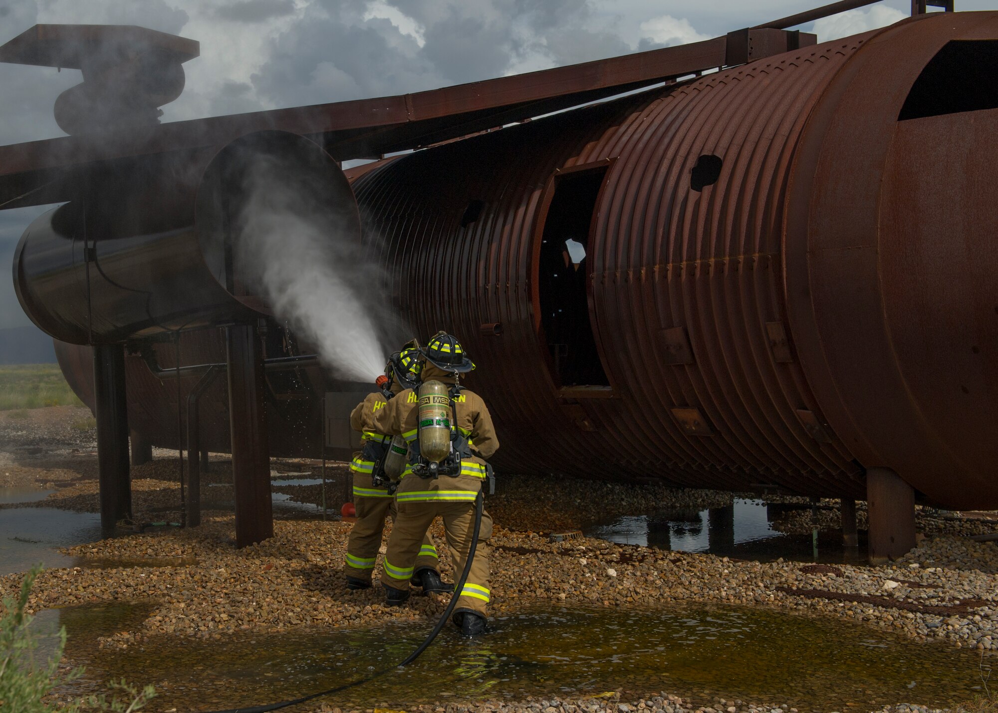 Staff Sgt. Phillips Daniels and Senior Airman Mark Dunford, 49th Civil Engineer Squadron Fire Protection Flight firefighters simulate extinguishing a number three engine fire while demonstrating the capabilities of the P-34 Rapid Intervention Vehicle at Holloman Air Force Base, N.M., Sept. 21. The RIV is three times more cost effective than the conventional firefighting vehicles. The combination of water and firefighting foam discharges at 1,350 pounds per square inch and increases the length of time that the RIV can remain on scene without having to be resupplied. Even though the RIV has a smaller capacity of 500 gallons, it has the firefighting capability of the larger 1,500 to 1,750 gallon vehicle at a cost that is significantly less. (U.S. Air Force photo by Airman 1st Class Aaron Montoya / Released)