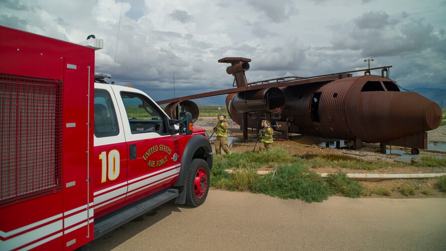 Staff Sgt. Phillip Daniels and Senior Airman Mark Dunford, 49th Civil Engineer Squadron Fire Protection Flight firefighters reset after extinguishing a simulated number three engine fire during a capability demonstration of the P-34 Rapid Intervention Vehicle at Holloman Air Force Base, N.M., Sept. 21. The RIV is three times more cost effective than the conventional firefighting vehicles. The combination of water and firefighting foam discharges at 1,350 pounds per square inch and increases the length of time that the RIV can remain on scene without having to be resupplied. Even though the RIV has a smaller capacity of 500 gallons, it has the firefighting capability of the larger 1,500 to 1,750 gallon vehicle at a cost that is significantly less. (U.S. Air Force photo by Airman 1st Class Aaron Montoya / Released)