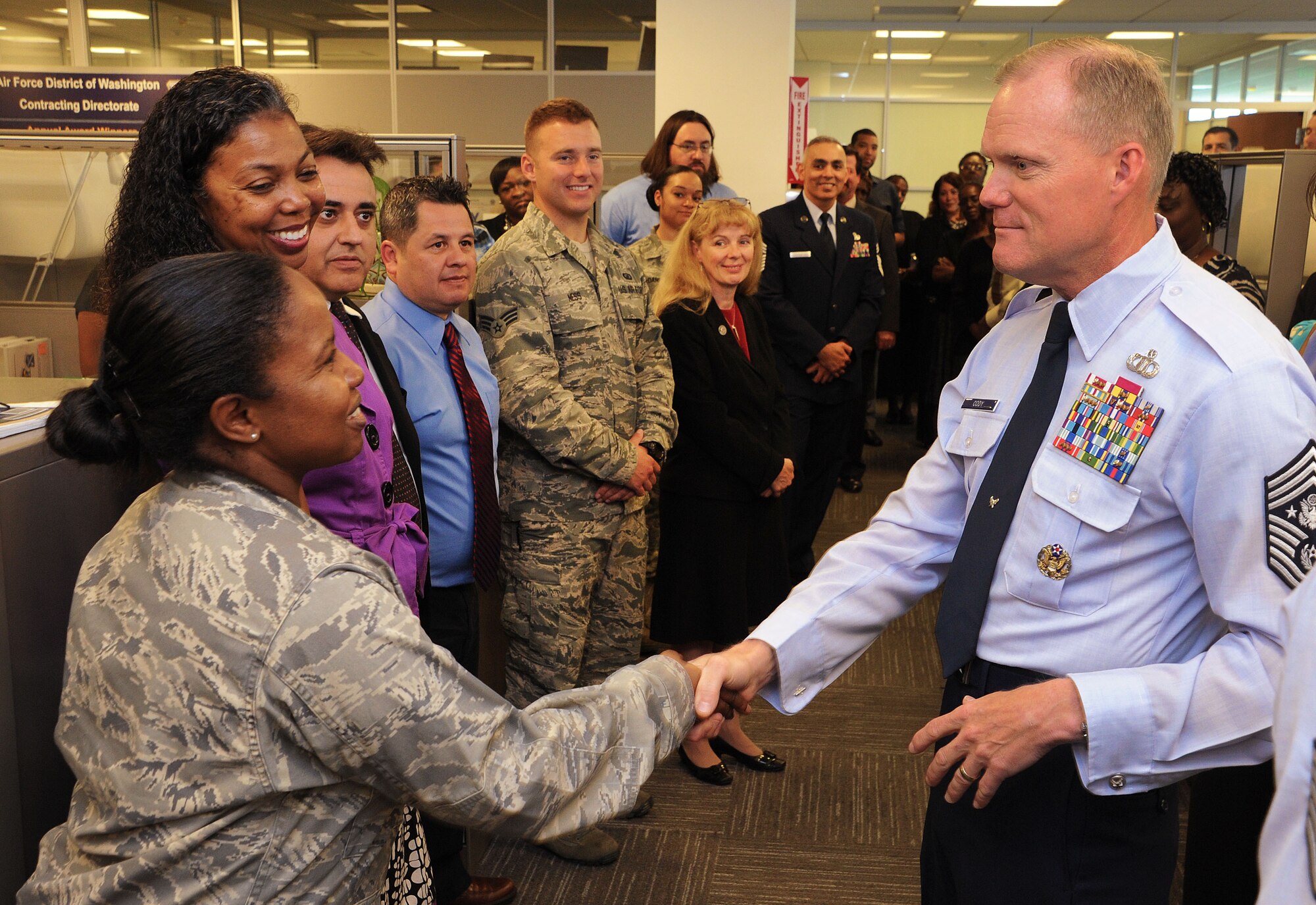 Chief Master Sgt. of the Air Force James A. Cody recognizes members of the Air Force District of Washington Contracting Division (left to right) Maj. Fabiola Bellevue, PK deputy director; Valerie Gaines, PKE division chief; Dereck Beavers, ...PKE branch chief; George Tamayo, contract specialist, Senior Airman Andrew Ness, contracting officer; and Elizabeth Hair, PK deputy director, for their guidance, coordination, and acquisition of a short notice contract at Joint Base Andrews, Maryland, Sept. 15, 2014. Cody coined each individual and thanked them personally for their hard work, attention to detail, and dedication to their profession and the U.S. Air Force. (U.S. Air Force photo/James E. Lotz)