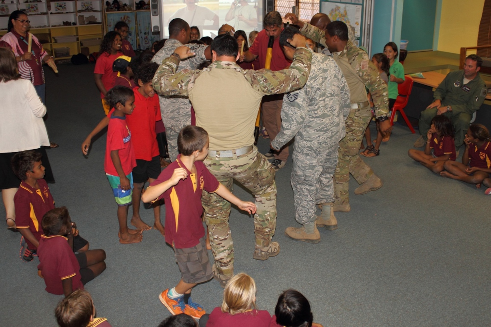 Deployed District of Columbia Air National Guard members dance a traditional Aboriginal dance with McFarlane Primary School students, accompanied by the school's cultural program director Arnold Vonsenden playing the didgeridoo during a visit, Sept. 17.  (U.S. Air National Guard photo/Airman 1st Class Aaron Church)