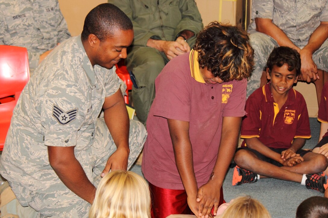 Staff Sgt. Malcom Williams, 113th Wing medical technician, assists a student in performing CPR on a first-aid training dummy during the District of Columbia Air National Guard's visit to McFarlane Primary School while deployed to Australia for exercises Pitch Black and Tri-Sling, Sept. 17. (U.S. Air National Guard photo/Airman 1st Class Aaron Church)