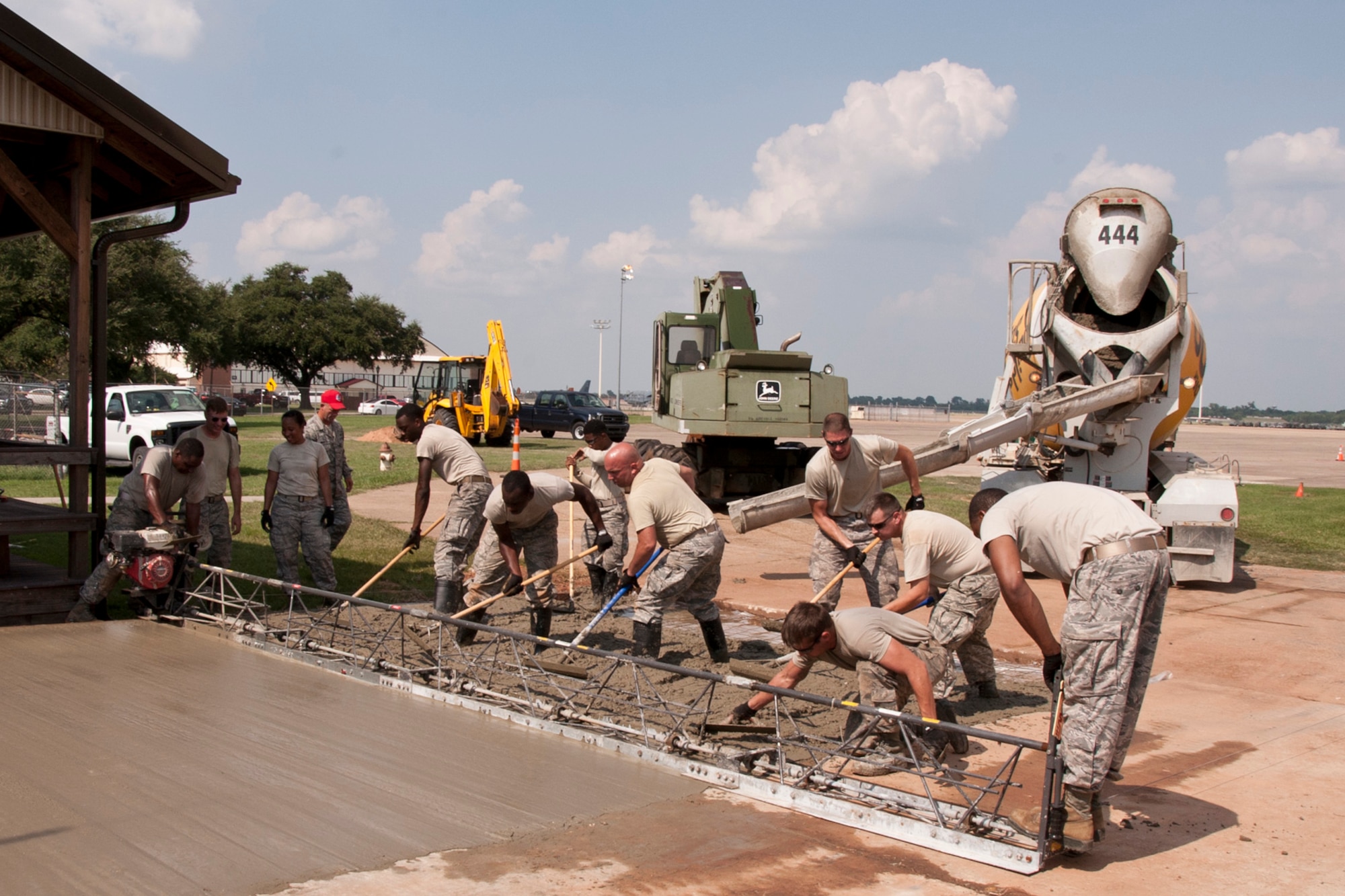 Airmen assigned to the 307th RED HORSE use a motorized concrete screed to strike off freshly placed concrete to make it as level as possible before finishing at the 93rd Bomb Squadron on Barksdale Air Force Base, La., Sept. 9, 2014. The new pad will be used for parking next to the building. (U.S. Air Force photo by Master Sgt. Jeff Walston/Released)