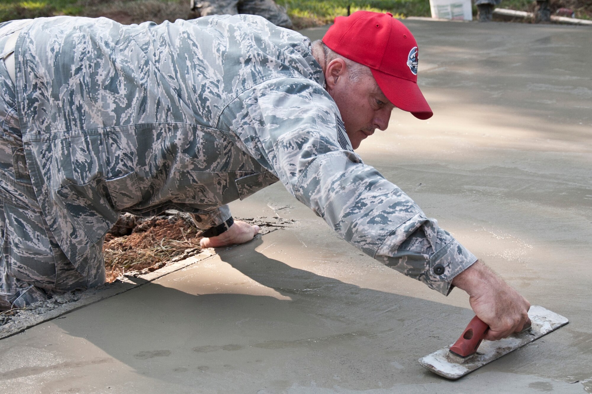 U.S. Air Force Chief Master Sgt. Rodney Kilby, chief of cantonment, 307th RED HORSE, uses a hand float to finish freshly poured concrete at Barksdale Air Force Base, La., Sept. 9, 2014. A total of four slabs were constructed and poured over a period of two days, three for new athletic equipment along one of the running trails and one for parking at the 93rd Bomb Squadron building. (U.S. Air Force photo by Master Sgt. Jeff Walston/Released)