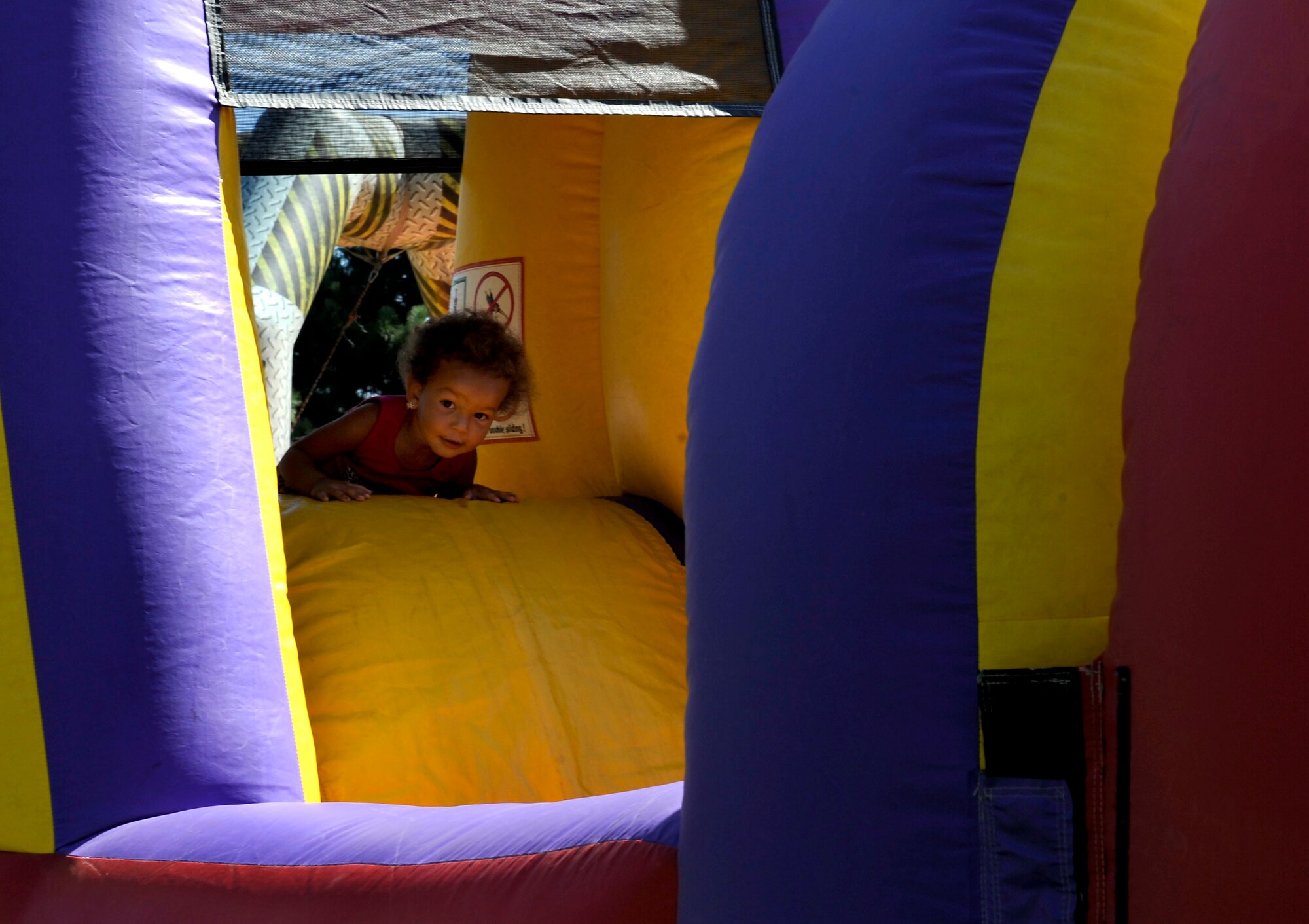PETERSON AIR FORCE BASE, Colo. - Tiana Sarrett, 2, makes her way through the inflatable obstacle course at the World Wide Day of Play held at Patriot Park Sept. 20 and hosted by the RP Lee Youth Center. Worldwide Day of Play is an annual event designed to encourage children and parents to turn off the television and get outside and play. The event had many activities for kids to enjoy, including a climbing wall, inflatable games and obstacle courses, and healthy snacks. (U.S. Air Force photo/Airman 1st Class Rose Gudex)
