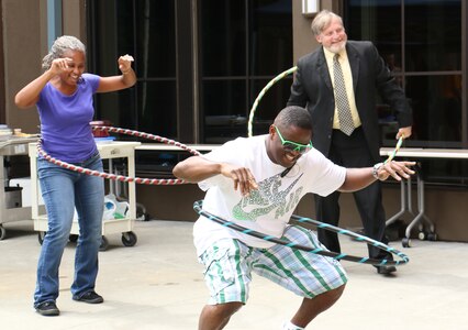 Naval Health Clinic Charleston staff members of compete in a hula-hoop contest during the NHCC Multicultural Command Picnic Sept. 19, 2014, at the clinic
grounds on Joint Base Charleston, S.C. From left to right: Helen German, NHCC travel officer;  Petty Officer 3rd Class William Tucker, NHCC information management technician; and J. Scott Jackson, NHCC Occupational Medicine Audiology, and Immunizations department head. (U.S. Navy photo/ Seaman Cody Meeks)
