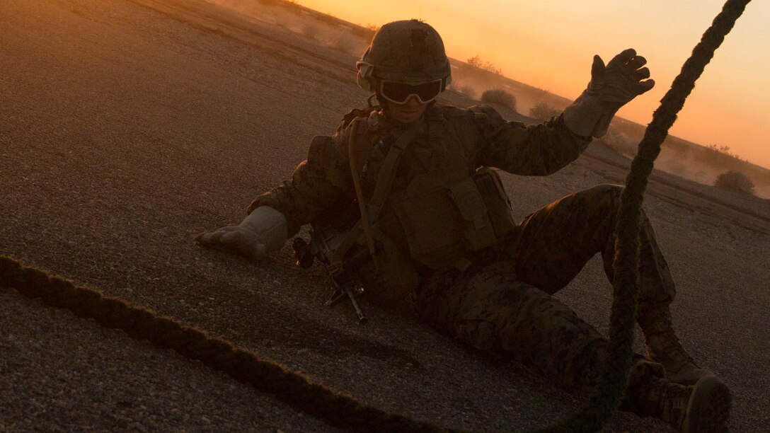 A Marine Infantry Officer Course student falls to the deck after descending from a CH-53E Super Stallion helicopter during a fast rope drill on the Marine Corps Air Station Yuma, Ariz., Auxiliary Landing Field 2, Wednesday, August 18, 2014. The fast rope training instilled in these Marines the skills necessary to complete IOC’s final exercise, Talon Reach IV.