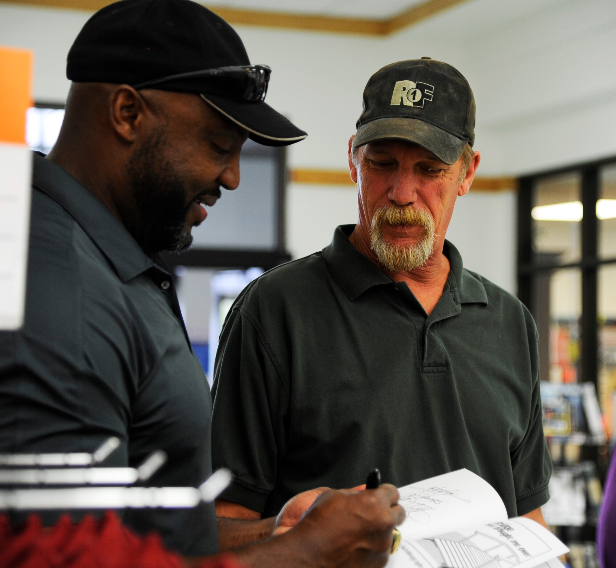 Fred Stokes, former NFL Washington Redskins player, signs his autograph for a fan during Retiree Appreciation Day at the Base Exchange on Hurlburt Field, Fla., Sept. 25, 2014. The meet and greet with the former NFL player was just one of the events to show appreciation to Hurlburt’s local retiree community. (U.S. Air Force photo/Staff Sgt. Sarah Hanson)