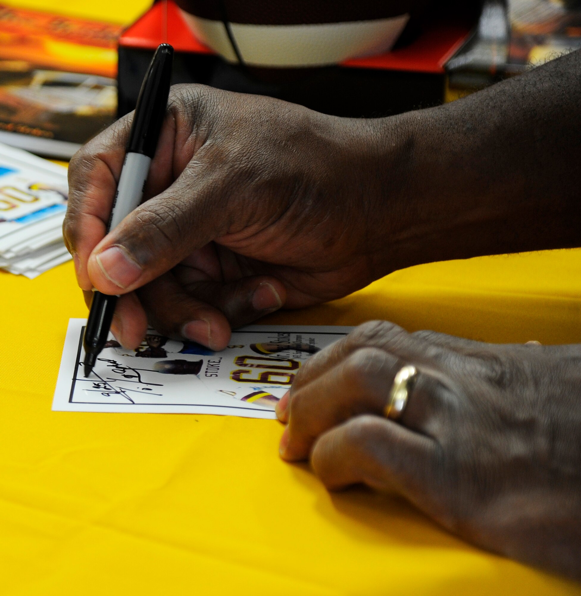 Fred Stokes, former NFL Washington Redskins player, signs his autograph for a fan during Retiree Appreciation Day at the Base Exchange on Hurlburt Field, Fla., Sept. 25, 2014. The event included various activities, such as free blood pressure checks and sidewalk sales to show retirees in the local community appreciation for their service to our country. (U.S. Air Force photo/Staff Sgt. Sarah Hanson)