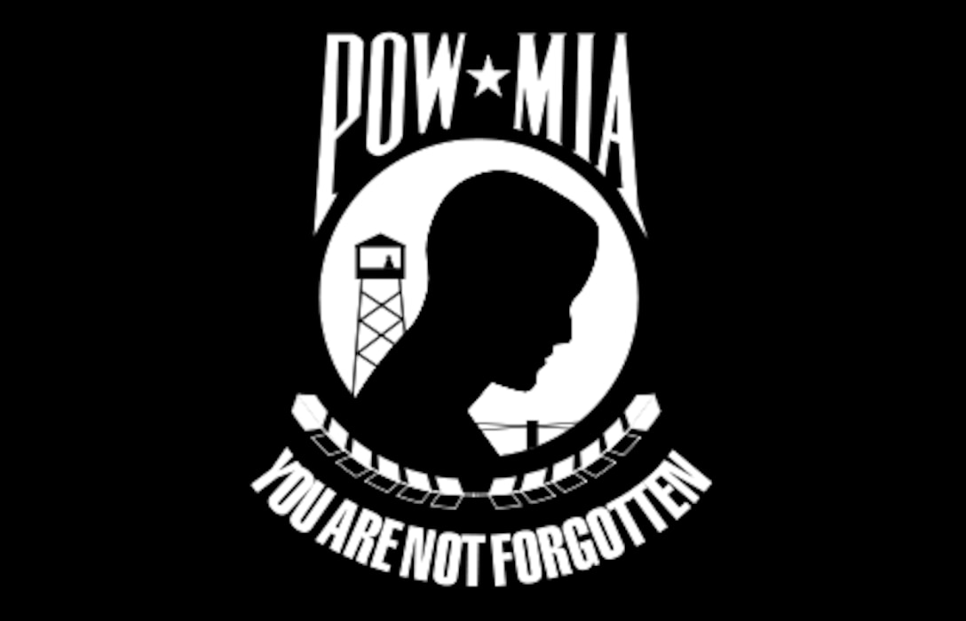 The flag is a black and white silhouette of a man with barbed wire and a tower in the background and is underscored by the words ‘You Are Not Forgotten.’