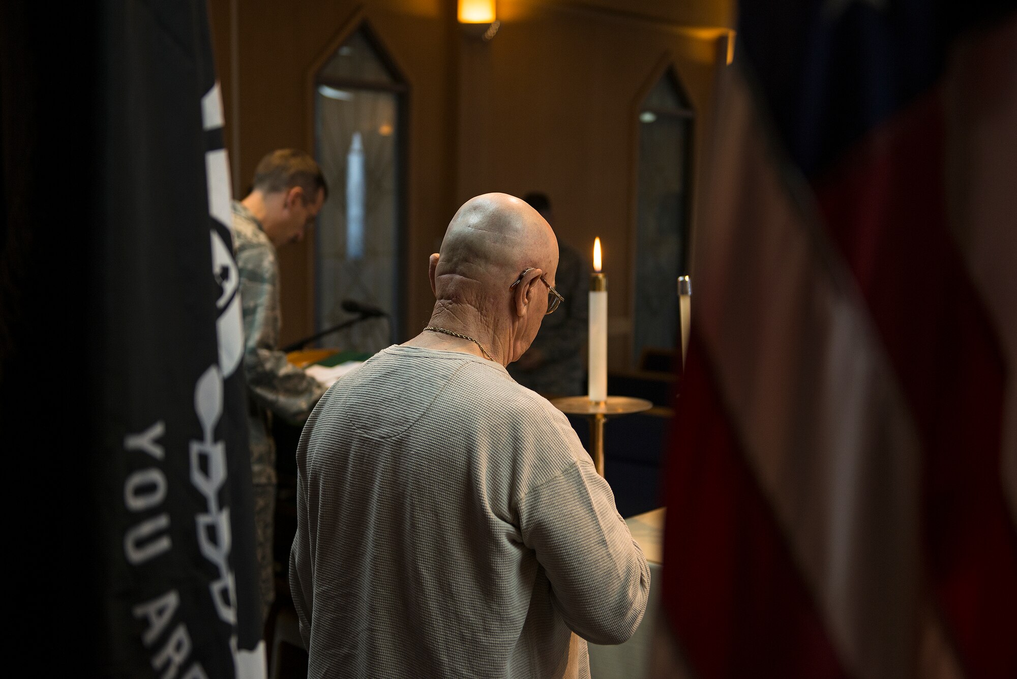 Ernest W. Lee, Veterans of Foreign Wars District III Korea commander, bows his head during a prayer at a Prisoner of War/Missing in Action candle-lighting vigil Sept. 23, 2014, at Osan Air Base, Republic of Korea. Team Osan observed POW/MIA remembrance week with the candlelighting ceremony, a reveille and retreat ceremony, a 24-hour run and a closing remembrance ceremony.(U.S. Air Force photo by Staff Sgt. Jake Barreiro/Released)