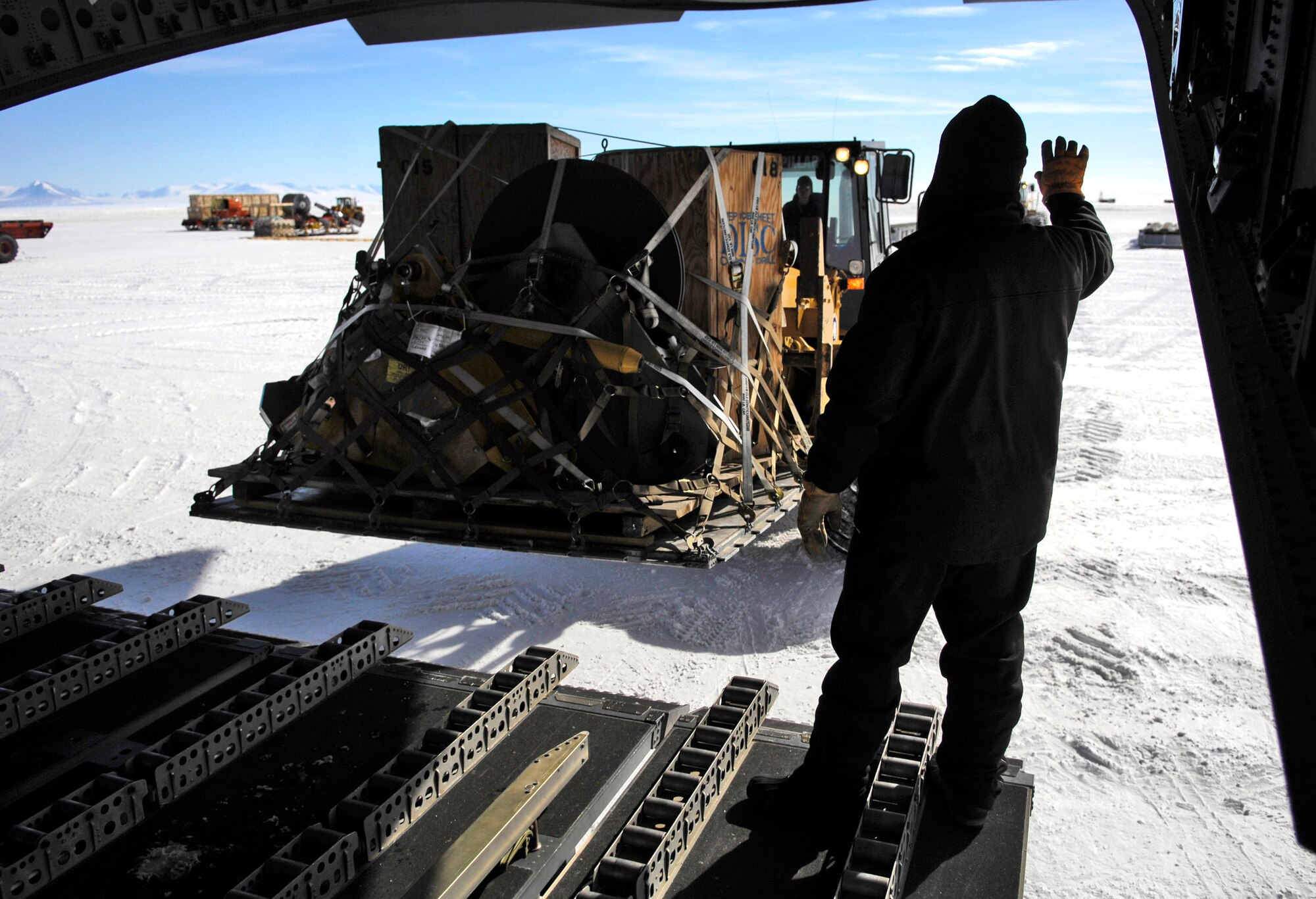 Tech. Sgt. Chris Albertson directs a forklift as it offloads cargo from a C-17 Globemaster III, Nov. 27, 2007, on the ice runway near McMurdo Station, Antarctica, during Operation DEEP FREEZE. Airlift for Operation DEEP FREEZE involves active duty and Reserve C-17 Globemaster III support from Joint Base Lewis-McChord, Wa., LC-130 Hercules support from the New York Air National Guard, sealift support from the U.S. Coast Guard and Military Sealift Command, engineering and aviation services from U.S. Navy Space and Naval Warfare Systems Command, and cargo handling from the U.S. Navy. (U.S. Air Force photo by Tech. Sgt. Shane A. Cuomo/Released)