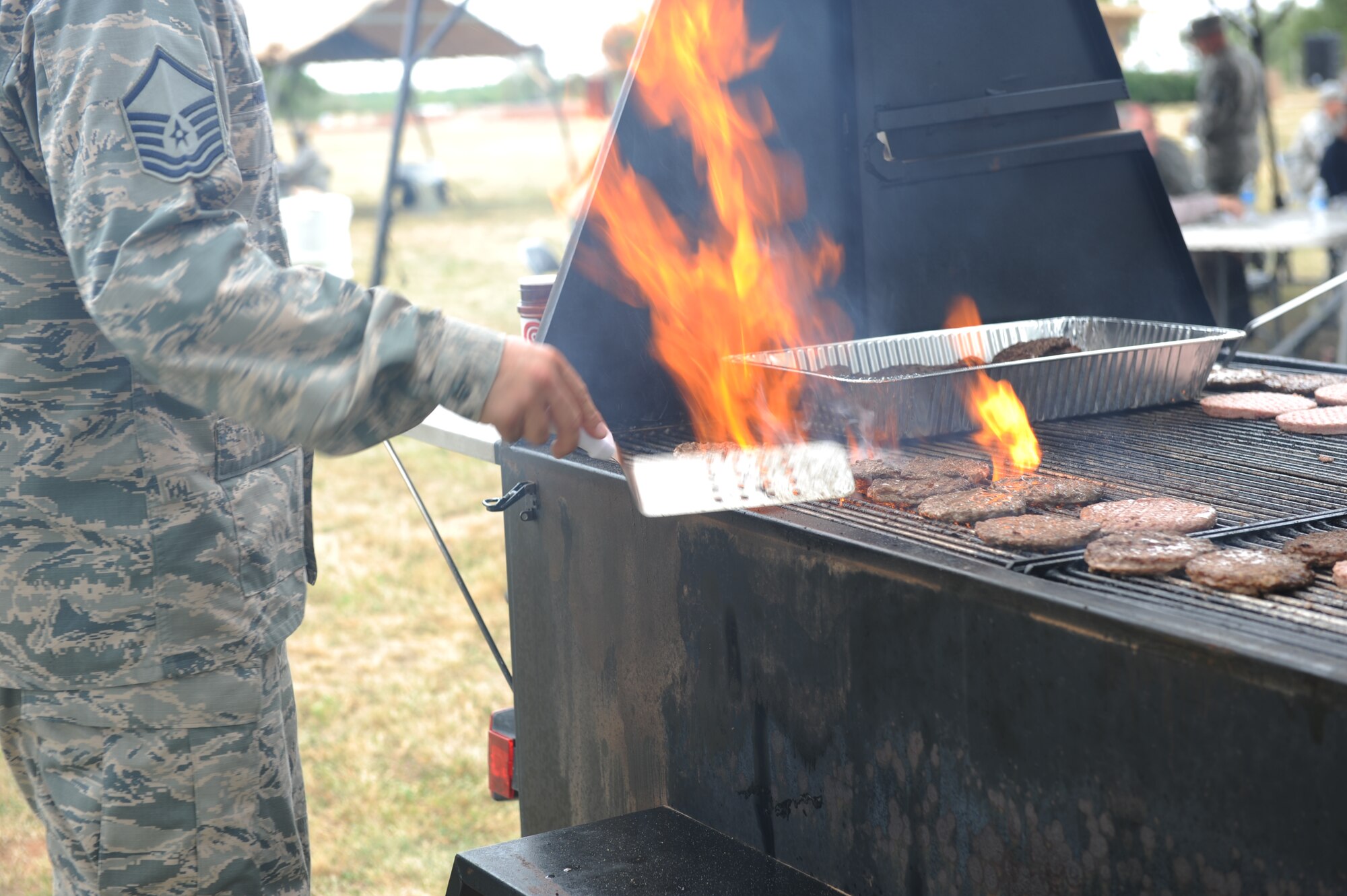 U.S. Air Force Master Sgt. Larry Hamlin, 317th Airlift Group first sergeant in-training, grills burgers during a cookout in support of a Comprehensive Airman Fitness (CAF) event Sept. 11, 2014, at Dyess Air Force Base, Texas. CAF events are hosted in order for Airmen to receive their required resilience training for each quarter. The program focuses on different aspects of Airmen’s lives, including mental, physical, social and spiritual fitness in order to be resilient. (U.S. Air Force photo by Airman 1st Class Autumn Velez/Released)