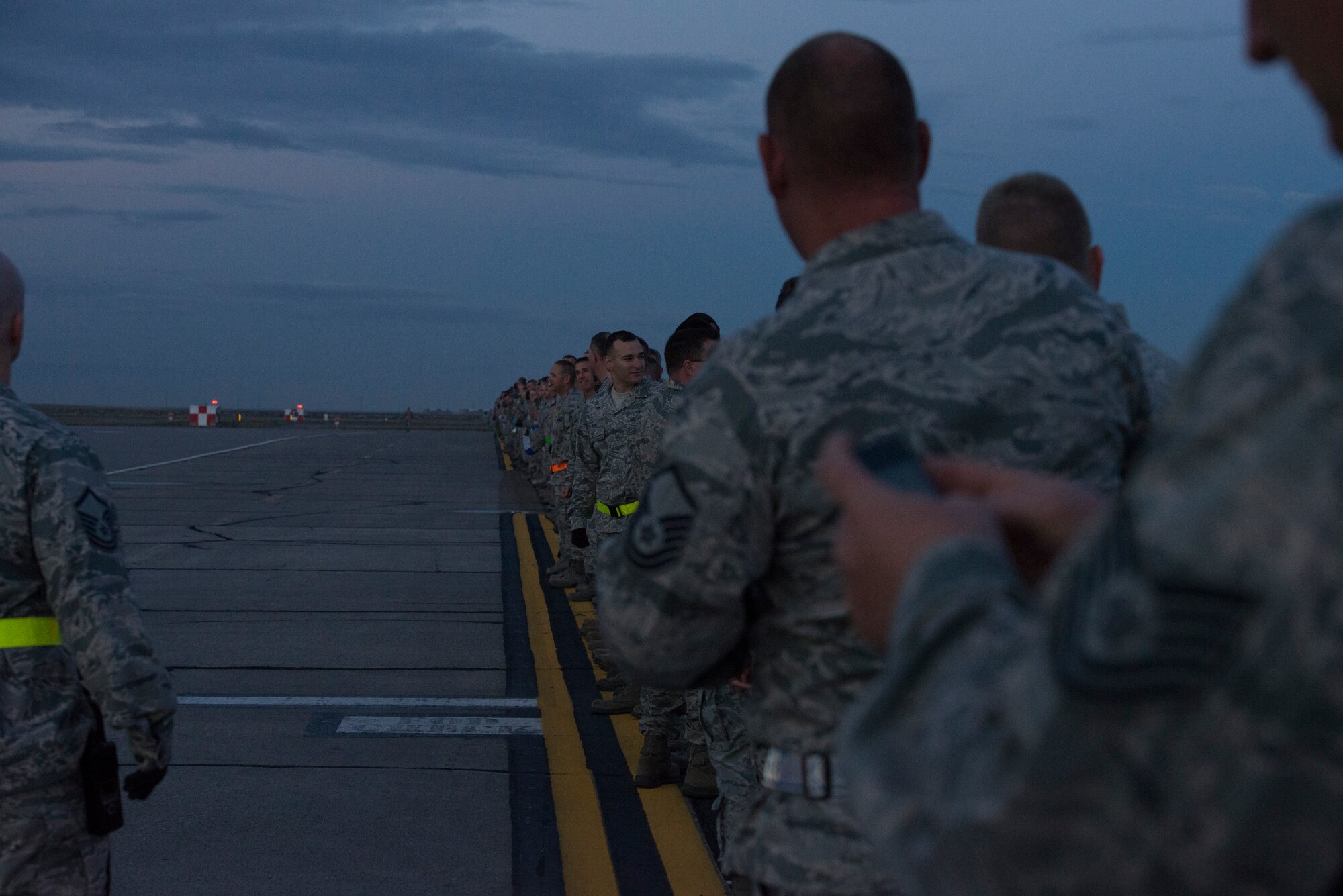 Service members of Mountain Home Air Force Base, Idaho, gather early in the morning to assist in a wing-wide FOD walk on the flightline, Sept. 22, 2014. Airfield management helped coordinate the event to get the flightline cleared for operation. (U.S. Air Force photo by Airman 1st Class Jessica Smith/RELEASED)