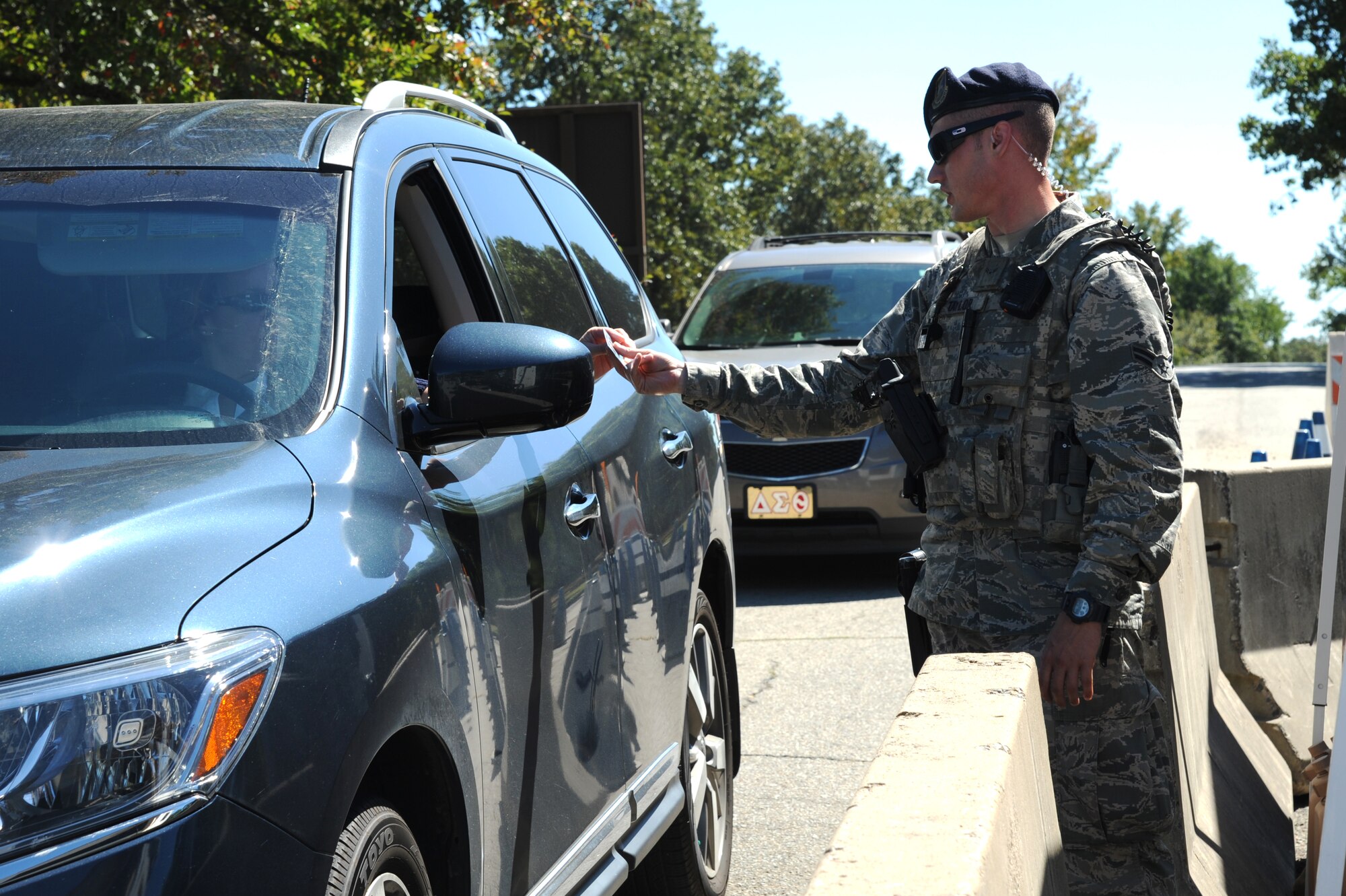Airman 1st Class Coty Taylor, a 19th Security Forces Squadron response force member, hands identification back to a driver at the Harris Road gate Aug. 22, 2014, at Little Rock Air Force Base, Ark. Taylor uses the entry control point established at the Harris Road gate to admit authorized personnel on base. (U.S. Air Force photo by Airman 1st Class Mercedes Muro) 