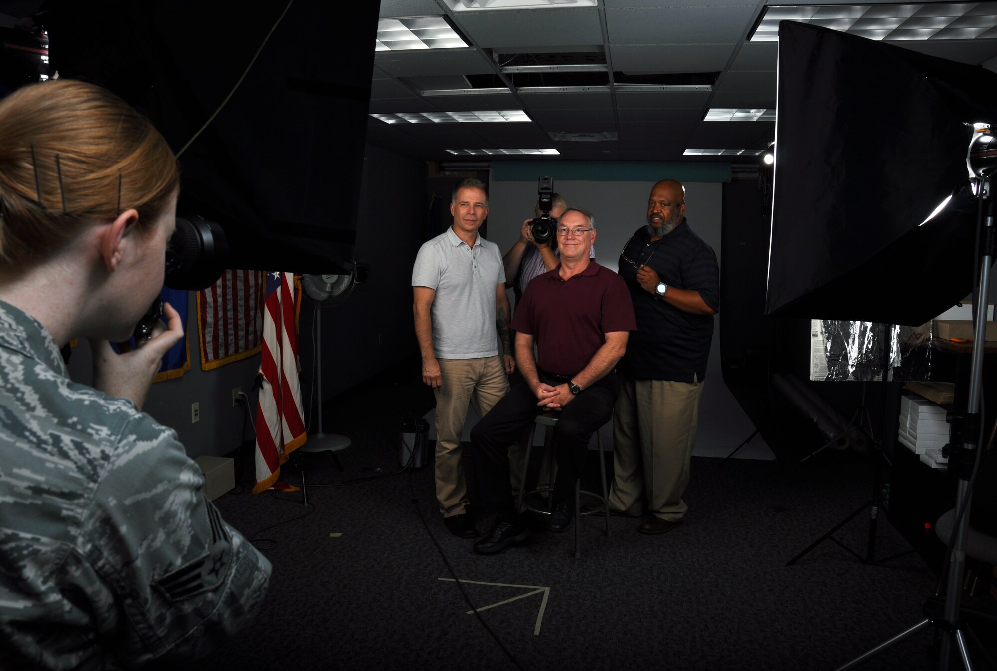 Senior Airman Madelyn Brown, 60th Air Mobility Wing Public Affairs photojournalist, takes a portriat photo of the Base Multimedia Service Center team in the studio at Travis Air Force Base Monday. From left to right is Ken Wright, Heide Couch with camera, Dave Cushman and T.C. Perkins. (U.S. Air Force photo/Staff Sgt. Christopher Carranza)