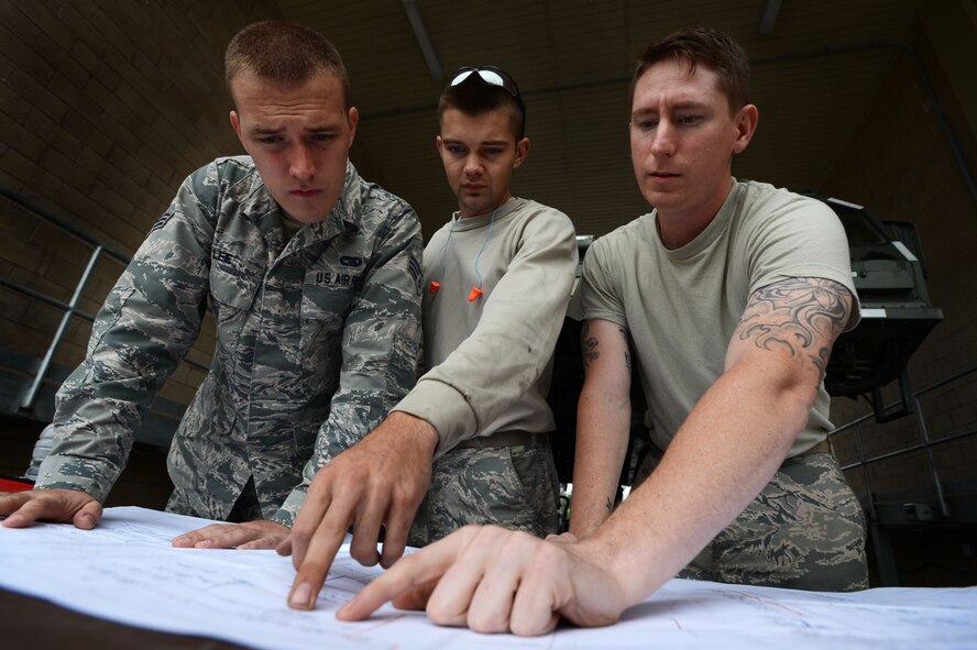 (From left) U.S. Air Force Senior Airman David Lee, Airman 1st Class Ryan Marney, and Staff Sgt. Dustin Ezernack, 20th Logistic Readiness Squadron vehicle maintenance mechanics, review an electrical schematics blueprint at Shaw Air Force Base, S.C., Sept. 25, 2014. During an approximate six-hour test, the three were evaluated on their capabilities to troubleshoot and perform maintenance on a Halvorsen 25K Cargo Loader.   (U.S. Air Force photo by Airman 1st Class Jensen Stidham/Released) 