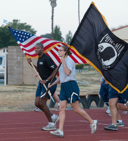 Master Sgt. Ryan Swanigan, 570th Global Mobility Squadron flight chief and Airman 1st Class Maria Settanni, 570th GMS unit training and deployment manager don't miss a step as they accept the United States and Prisoner of War flags from their squadron team members running in the 24 Hour POW/MIA Relay Run at the fitness Center at Travis Air Force Base Sept. 19. More than 250 Travis members took part in the run to honor and remember the 83,000 American service members missing in action since World War II, those who were captured by enemy forces, and the family members who were left behind. (U.S. Air Force Photo/Heide Couch)