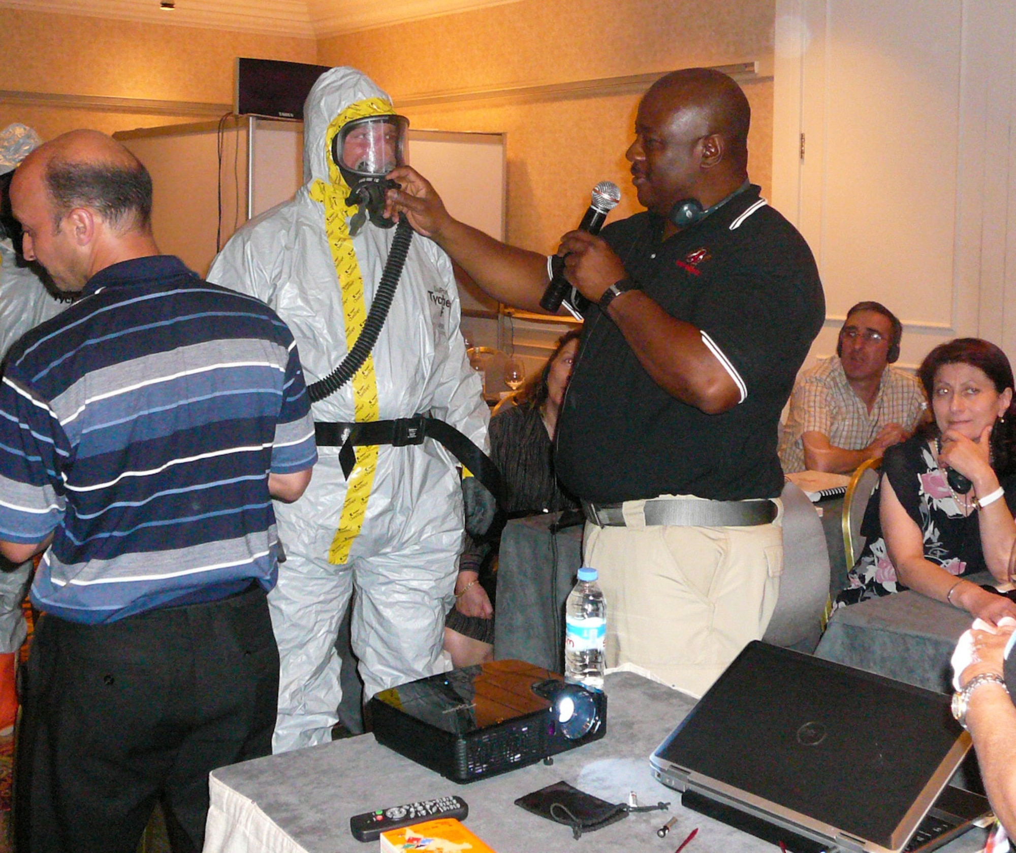 U.S. Air Force Master Sgt. Glen McIver, standing right, a medic with the 116th Medical Group (MDG), Georgia Air National Guard, demonstrates the proper wear of a protective suit and mask used in chemical environments while teaching a class in the Republic of Georgia, Sept. 9, 2014. McIver and eight members from the 116th MDG, based out of Robins Air Force Base, Ga., were invited to the Republic of Georgia by the U.S. European Command to teach physicians, infectious disease experts and hazmat response teams about treating patients in a chemical, biological, radiological, nuclear and high-yield explosive environment. The trip is one of more than 10 engagements in 2014 by Georgia National Guardsmen in what has been an ongoing 19-year relationship with the country as a part of the Department of State's Partnership for Peace program. (U.S. Air National Guard photo by Chief Master Sgt. Cynthia Haines/Released)
