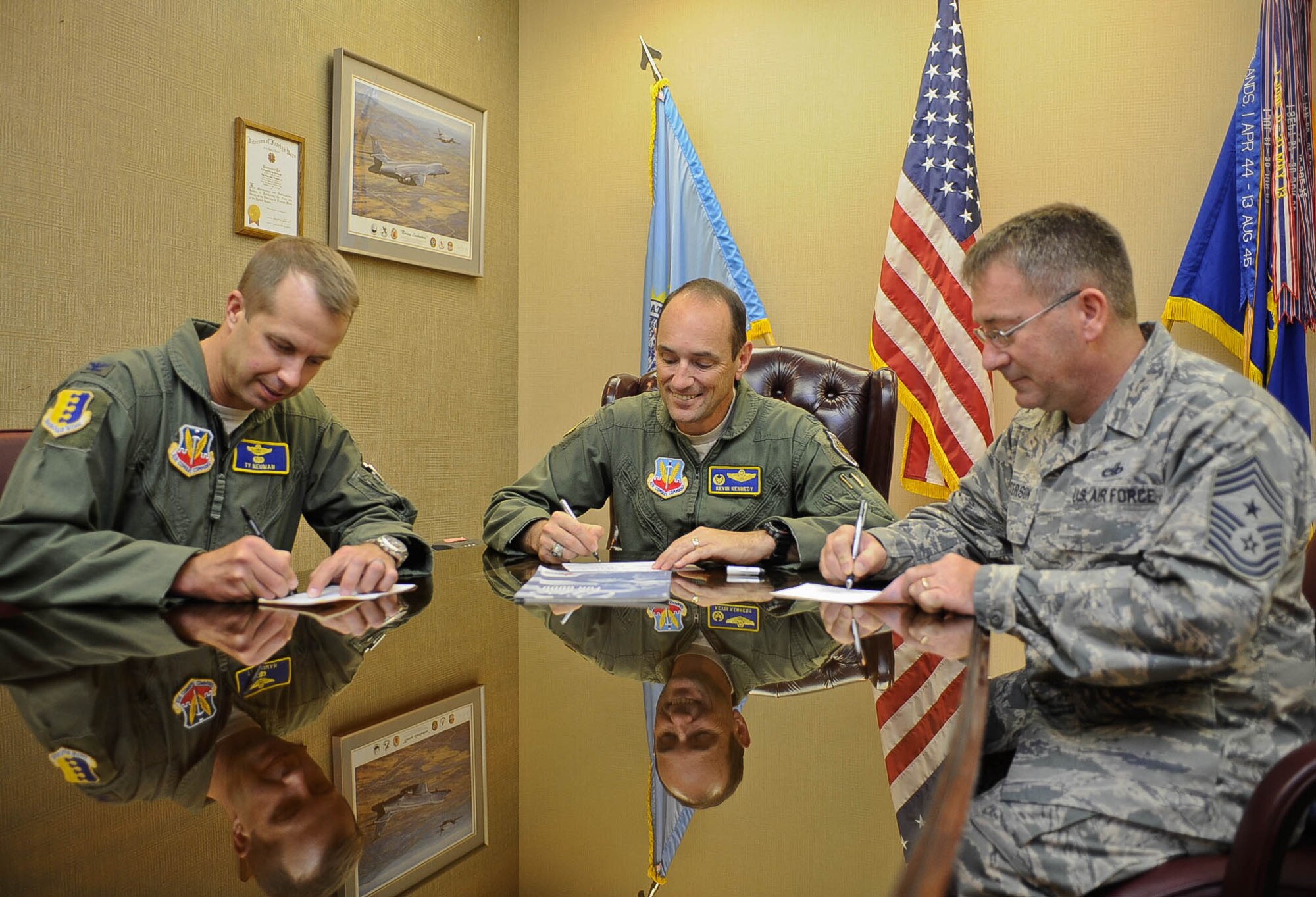 Col. Kevin Kennedy(middle), 28th Bomb Wing commander, Col. Ty Neuman (left), 28th BW vice commander, and Chief Master Sgt. Kevin Peterson, 28th BW command chief, sign Combined Federal Campaign donation forms in the 28th Bomb Wing Headquarters building at Ellsworth Air Force Base, S.D., Sept. 24, 2014. The Combined Federal Campaign gives donators the choice to give to any local national or international charity by simply filling out a donation form and giving it to their designated CFC representative or to the nearest CFC office. (U.S. Air Force photo by Senior Airman Zachary Hada/Released)