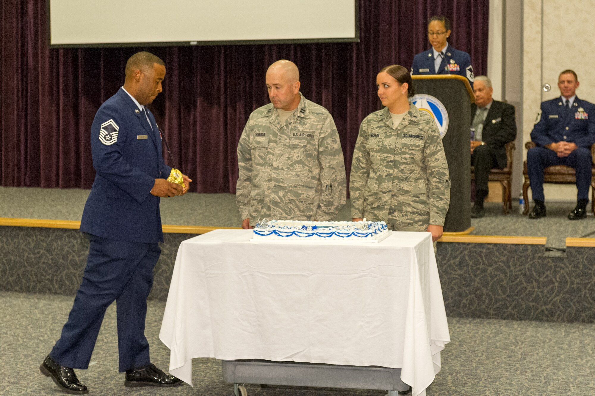 (left) Senior Master Sgt. Joshua McGee, Air Force Technical Applications Center, presents a ceremonial sword to Capt. Steven Svoboda and 1st Lt. Lori Brown, the oldest and youngest students in the Defense Equal Opportunity Management Institute Equal Opportunity Advisor Course, Class 14-3, Sept. 19, at Patrick Air Force Base, Fla. The duo cut the first piece of the Air Force's 67th birthday cake during a DEOMI ceremony, in which Chief Master Sgt. Craig Neri, 45th Space Wing command chief was guest speaker for the celebration. (U.S. Air Force photo/Cory Long) (Released)