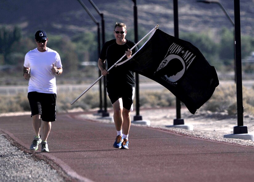 Senior Master Sgt. James Robbins, 99th Ground Combat Training Squadron superintendent of operations, left, and Col. James Chittenden, 432nd Wing/432nd Air Expeditionary Wing vice commander, start a 24-hour vigilance run Sept. 18, 2014, at Creech Air Force Base, Nevada. The vigilance took place as part of POW/MIA Remembrance Week and honored the more than 83,000 still unaccounted-for U.S. servicemembers. (U.S. Air Force photo by Airman 1st Class Christian Clausen/Released)