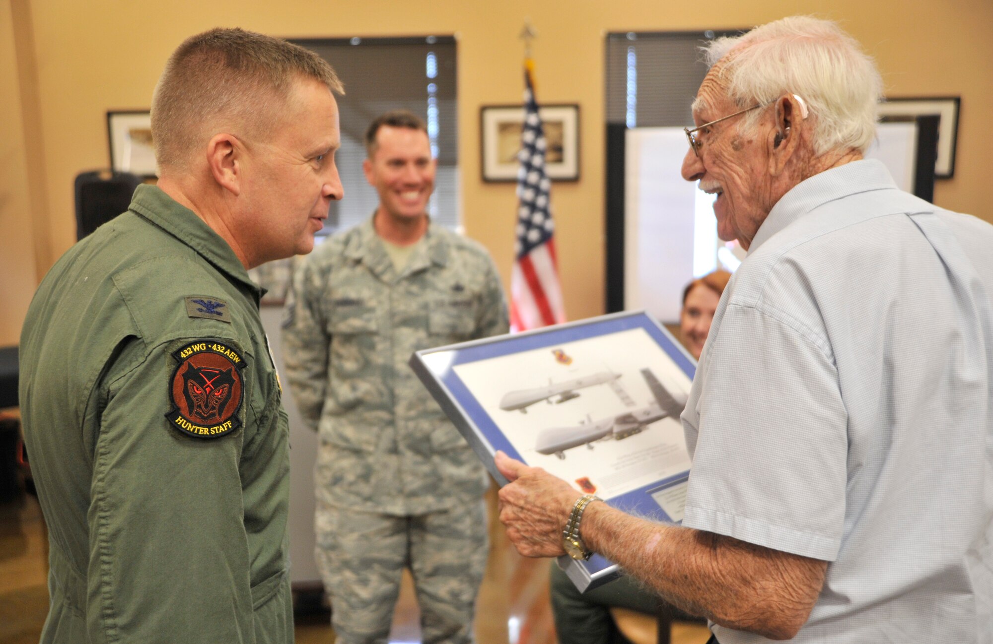 Col. James Cluff, 432nd Wing/432nd Air Expeditionary Wing commander, left, presents retired 2nd Lt. William Whitaker with the wing’s lithograph Sept. 15, 2014, at Creech Air Force Base, Nevada. Whitaker spoke to more than 100 Airmen about his time as a prisoner of war in the Army Air Corps at a breakfast as part of POW/MIA Remembrance Week. (U.S. Air Force photo by Airman 1st Class Christian Clausen/Released)