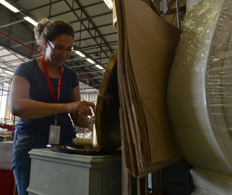 Andrea Noggle, vendor at the Ramstein Welfare Bazaar, prepares French painted vintage items before the start of the event on Ramstein Air Base, Germany, Sept. 20, 2014. Items varying from hand-made wooden clocks to Polish pottery were sold to more than 28,000 patrons over the span of the four-day 50th anniversary event. (U.S. Air Force photo/Senior Airman Holly Mansfield)